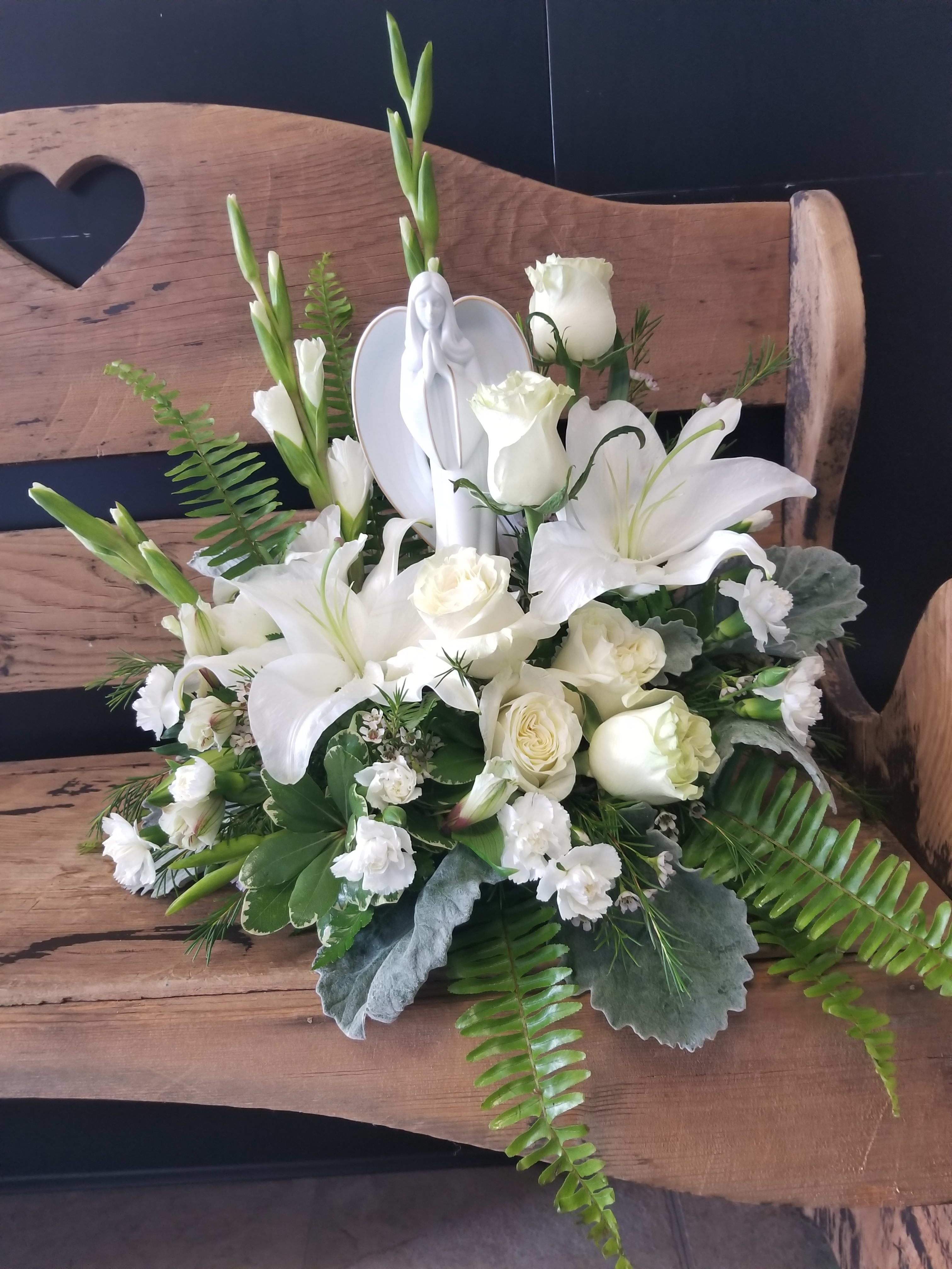 White floral arrangement with lilies and roses on a wooden bench