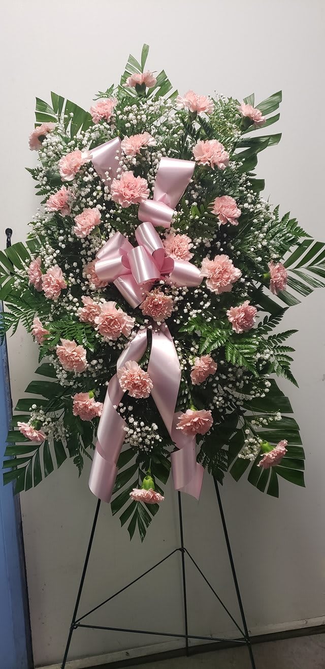 Pink carnation standing spray with a large pink ribbon on an easel