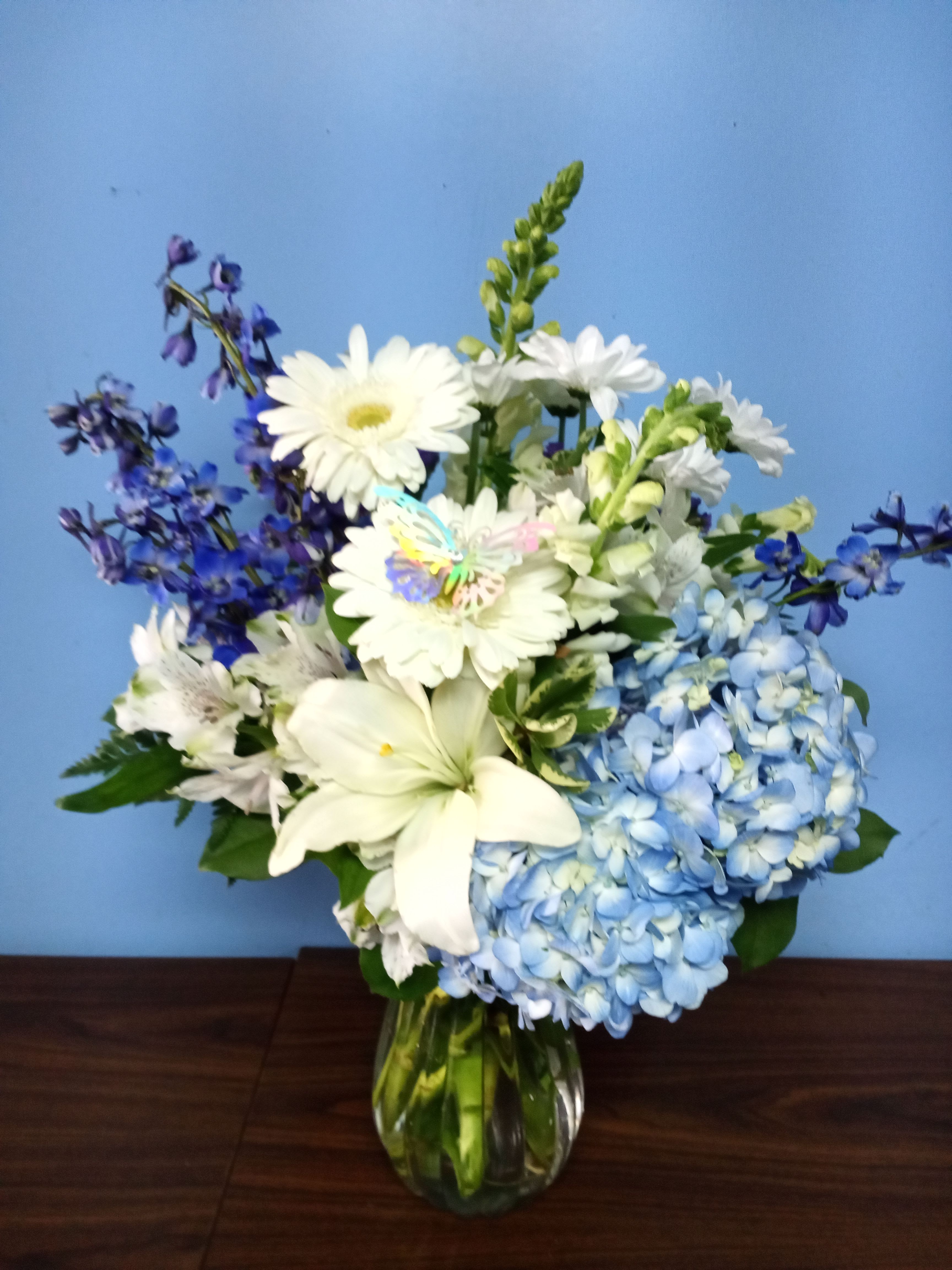 White daisies and blue hydrangeas in a glass vase