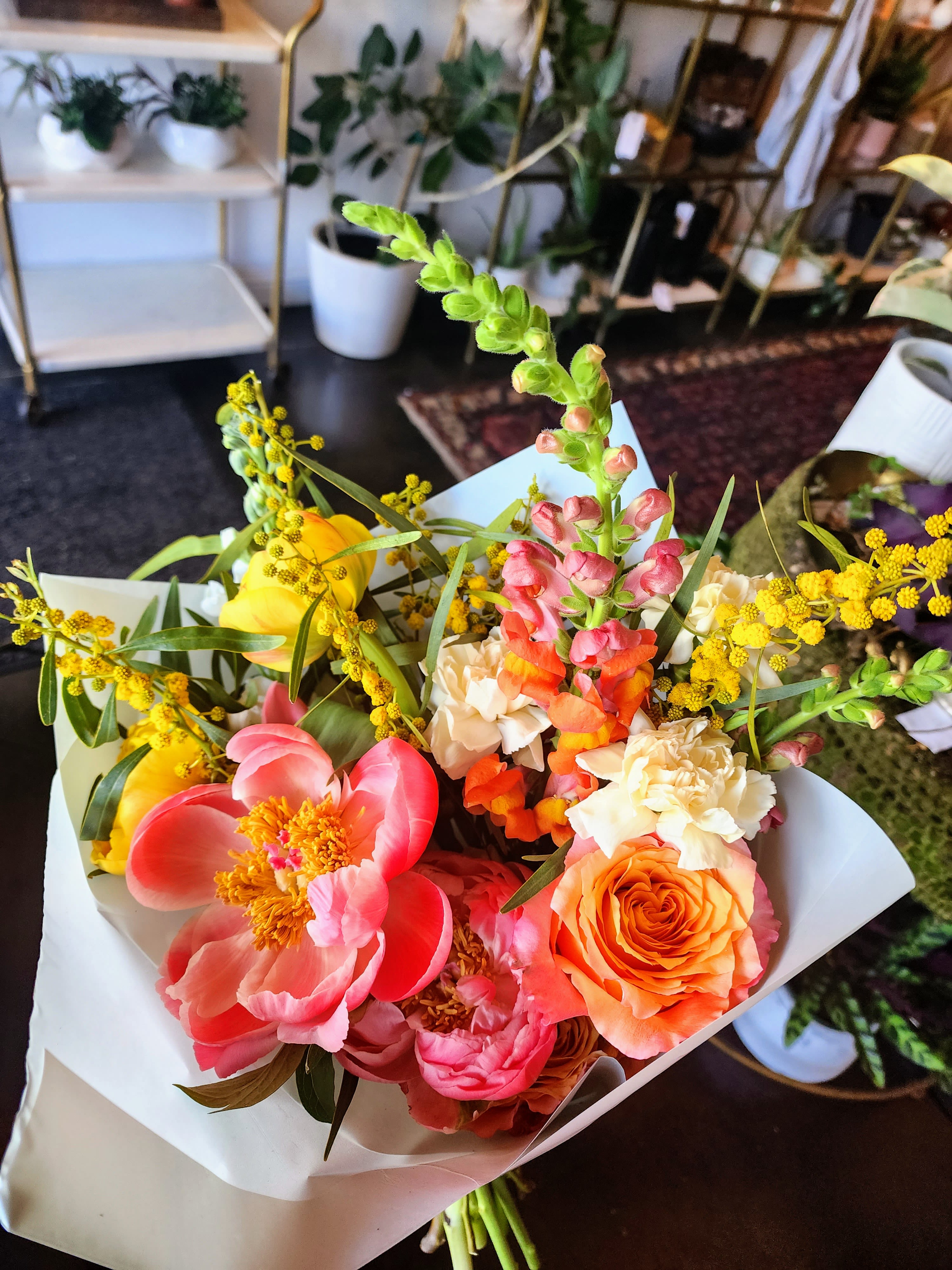 Luxe Wrap Bouquet Bright + Cheery - Bold, bright, and unapologetically beautiful—our Luxe Wrap Bouquet is designed for the girl who loves color that makes a statement. Bursting with hot pinks, vibrant corals, sun-kissed yellows, and energetic pops of orange, this hand-tied wrap feels like spring in full bloom with a confident, modern edge.  Each bouquet is thoughtfully designed in a lush garden style, blending airy movement with high-impact color for that effortlessly “put-together but still wild” look. Wrapped in signature paper and finished with a luxe touch, it’s perfect for gifting, celebrations, or simply brightening your space with something unforgettable.  No two wraps are ever exactly alike—each one is uniquely designed, making every bouquet a one-of-a-kind floral moment.  Bright. Bold. Luxe.  Please note that the flower varieties pictured may vary due to seasonal availability. However, rest assured that you will receive premium, fresh blooms of equal or greater value, ensuring a beautiful and high-quality arrangement every time.  If any elements of design are of major importance to your order, please include them in the Order Notes section at checkout, or please call or email us directly.