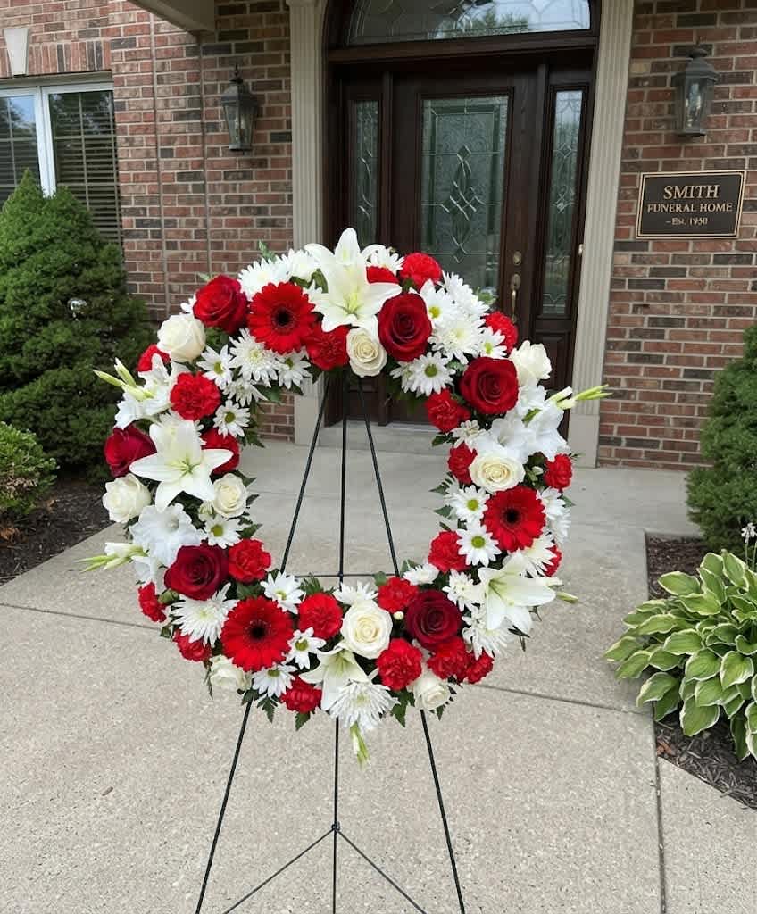 Red, white, and pink floral wreath on a stand outside a funeral home