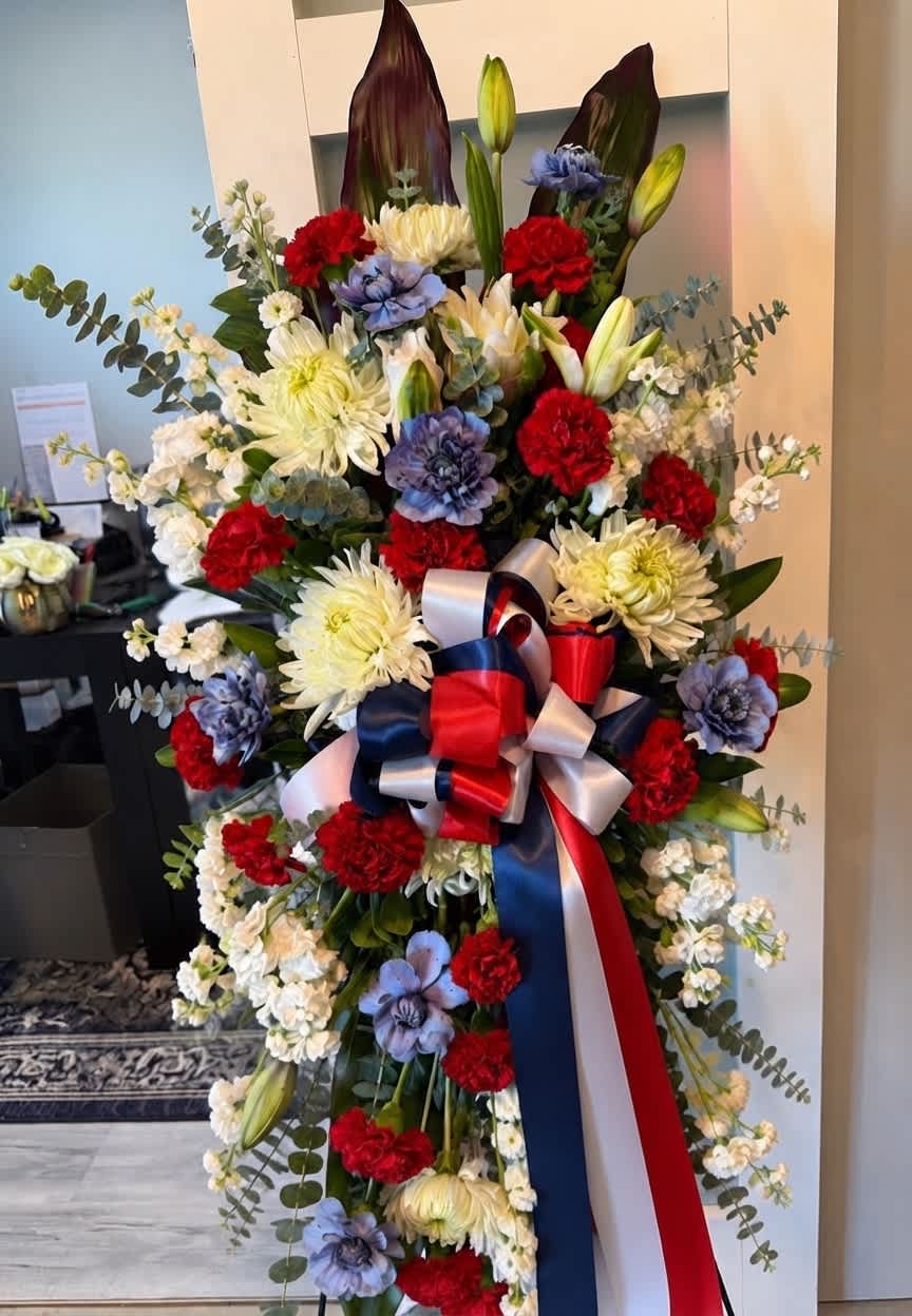 Standing floral spray with red, white, and blue flowers and a ribbon bow
