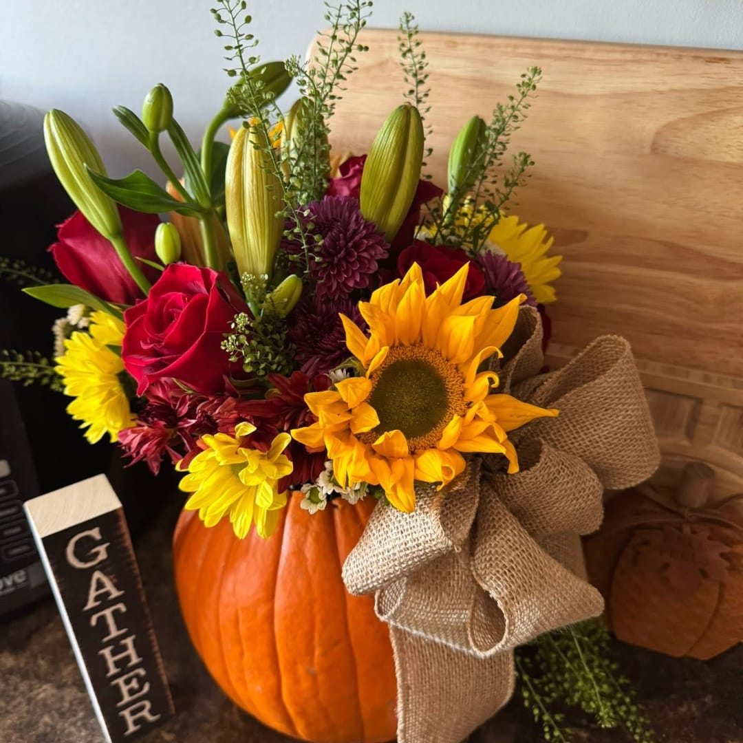 Fall floral arrangement in a pumpkin with sunflowers, roses, and lilies