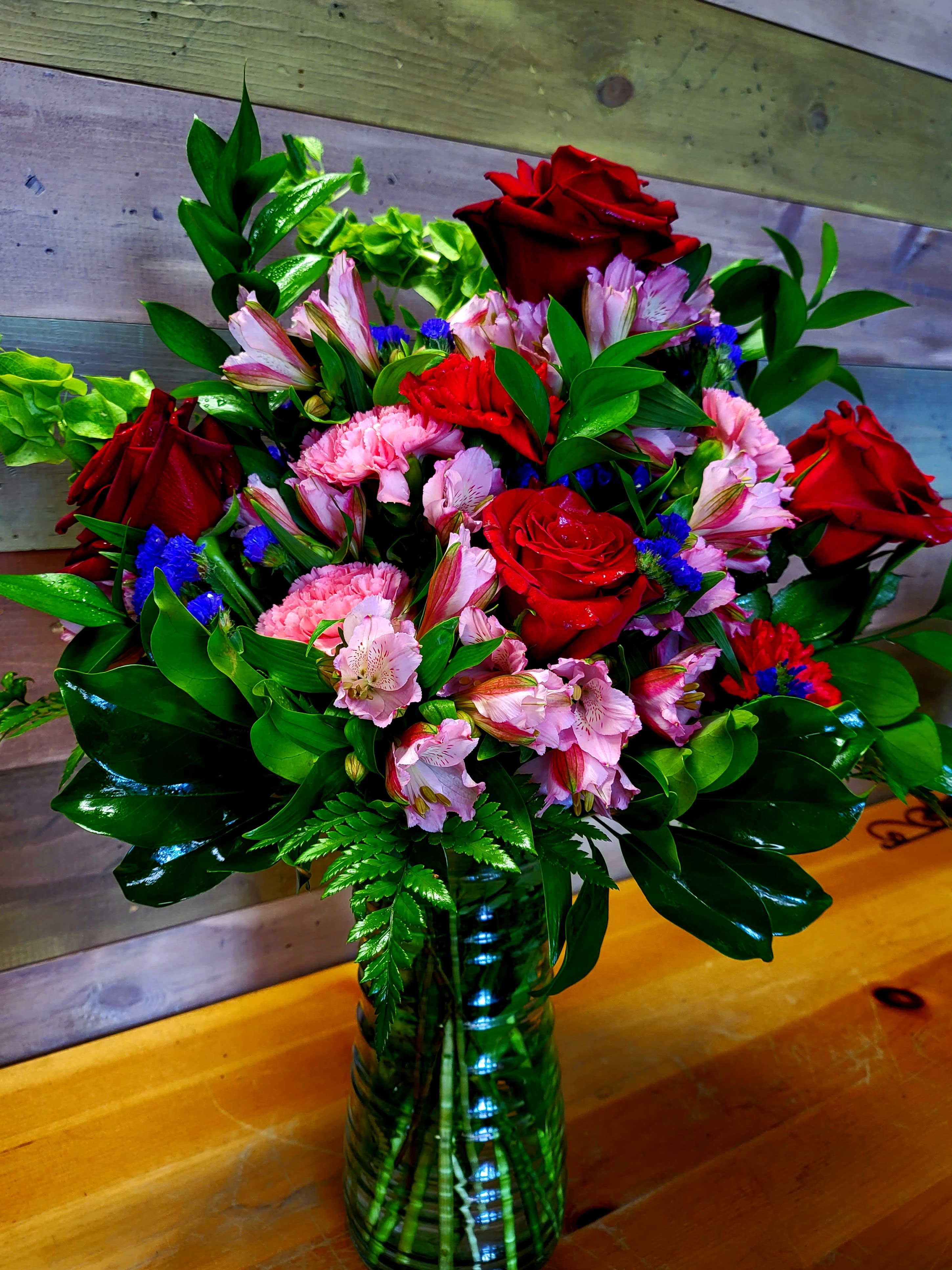 Bouquet of red roses, pink alstroemeria, and carnations in a glass vase