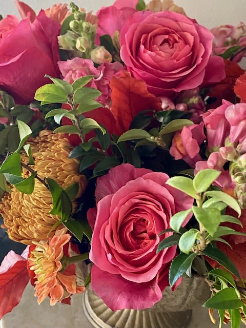Pink roses and orange blooms arranged in a vase