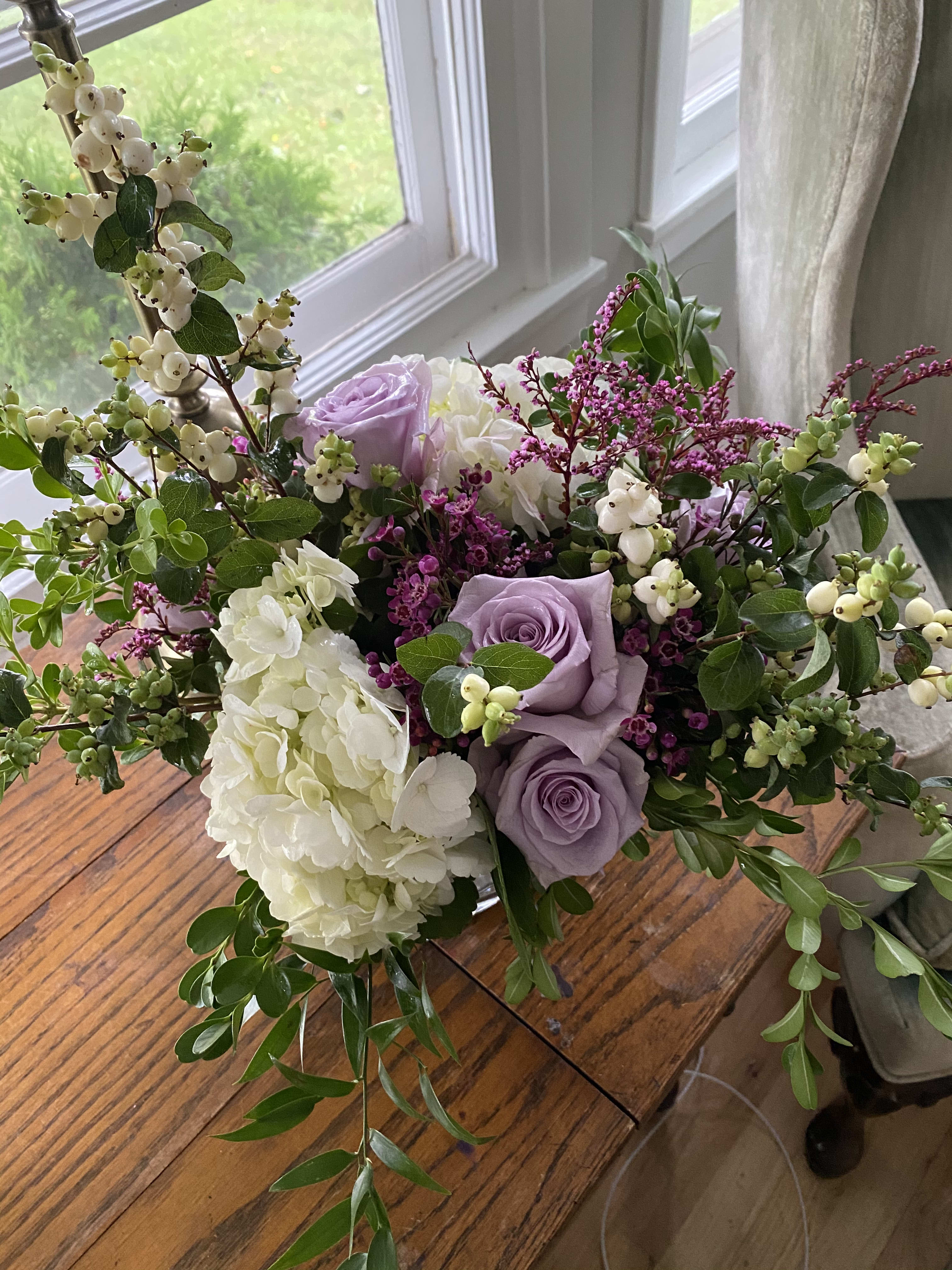 Lavender roses and white hydrangeas in a loose bouquet with berry branches