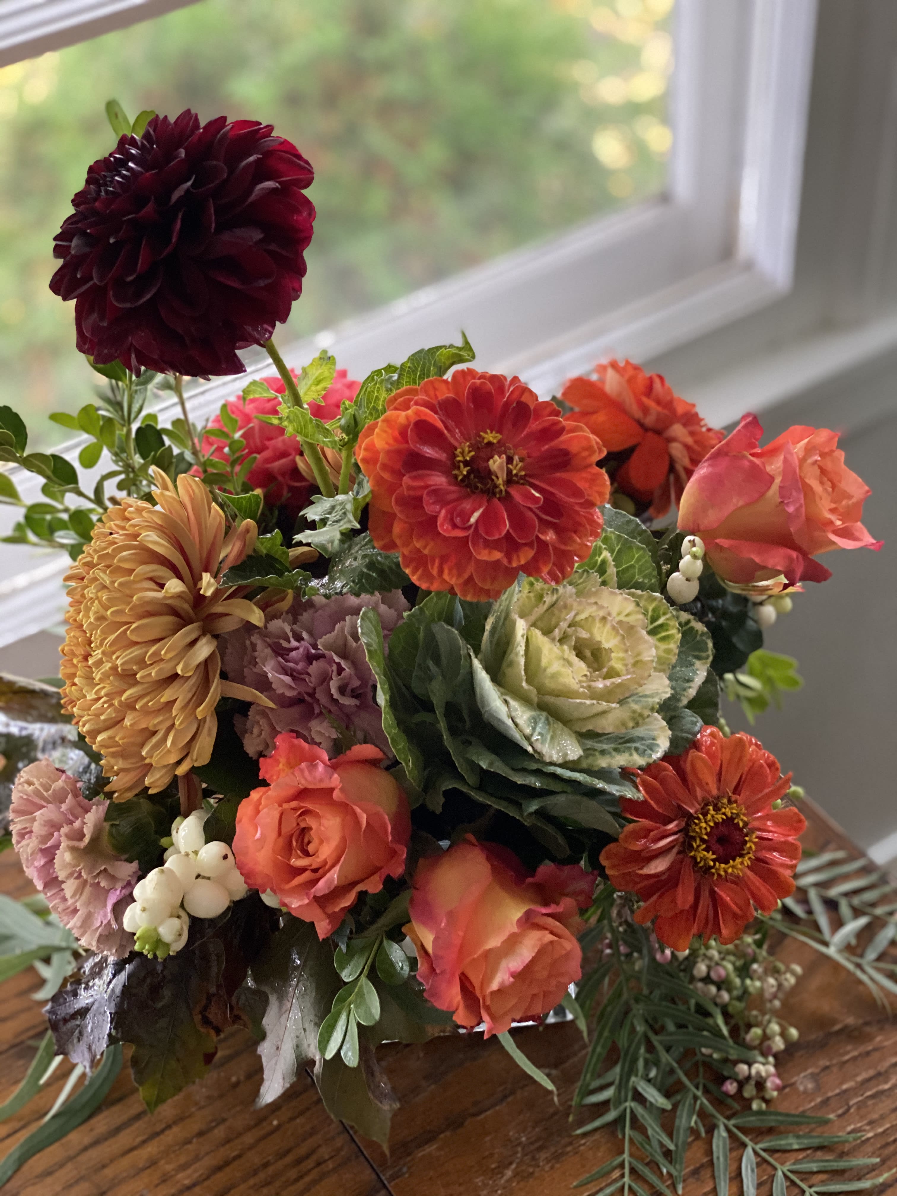 Mixed bouquet of orange, pink, and burgundy flowers in a vase