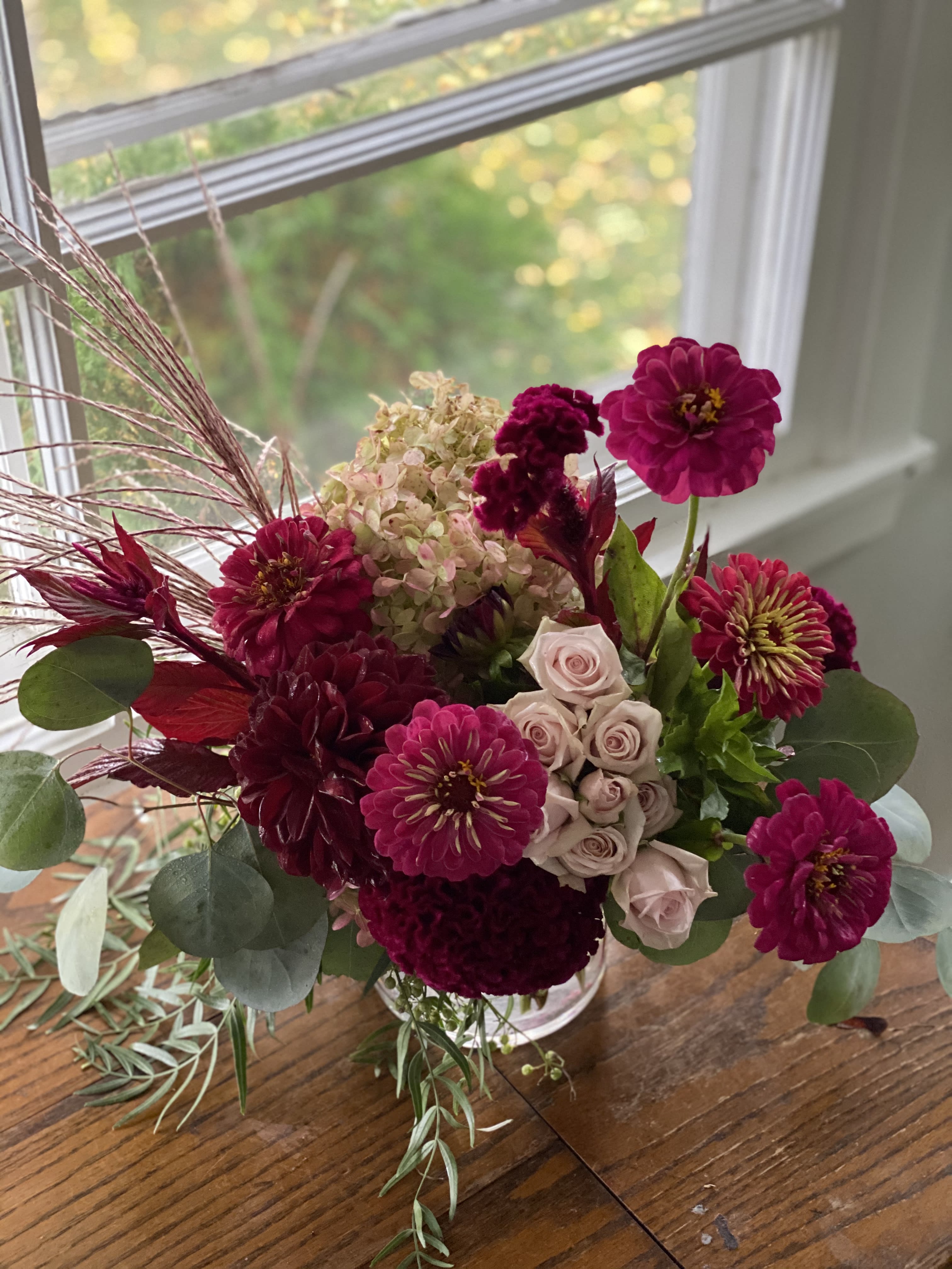 Bouquet of magenta and blush flowers in a clear glass vase
