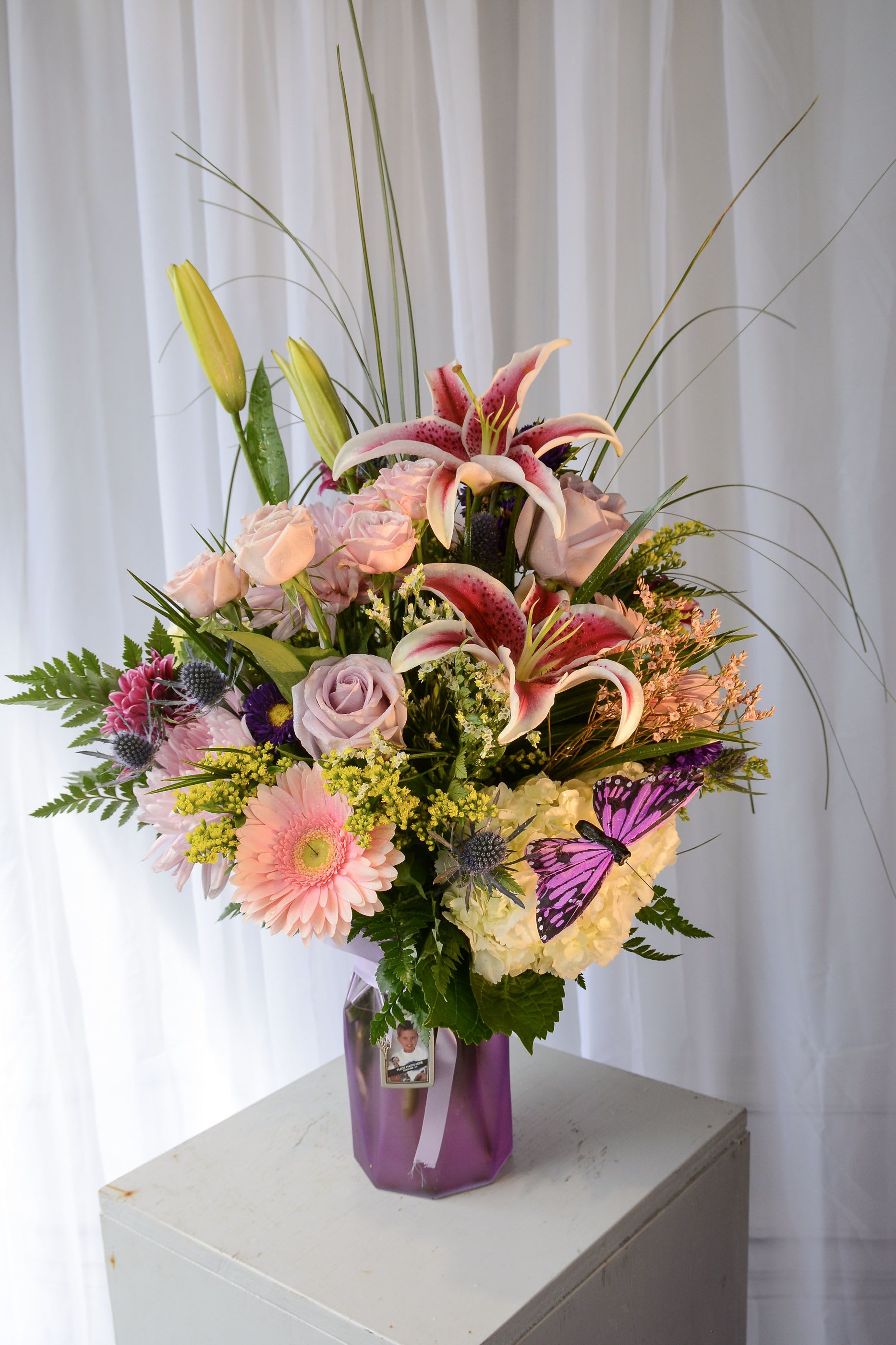 Mixed bouquet with pink lilies, roses, and a purple vase