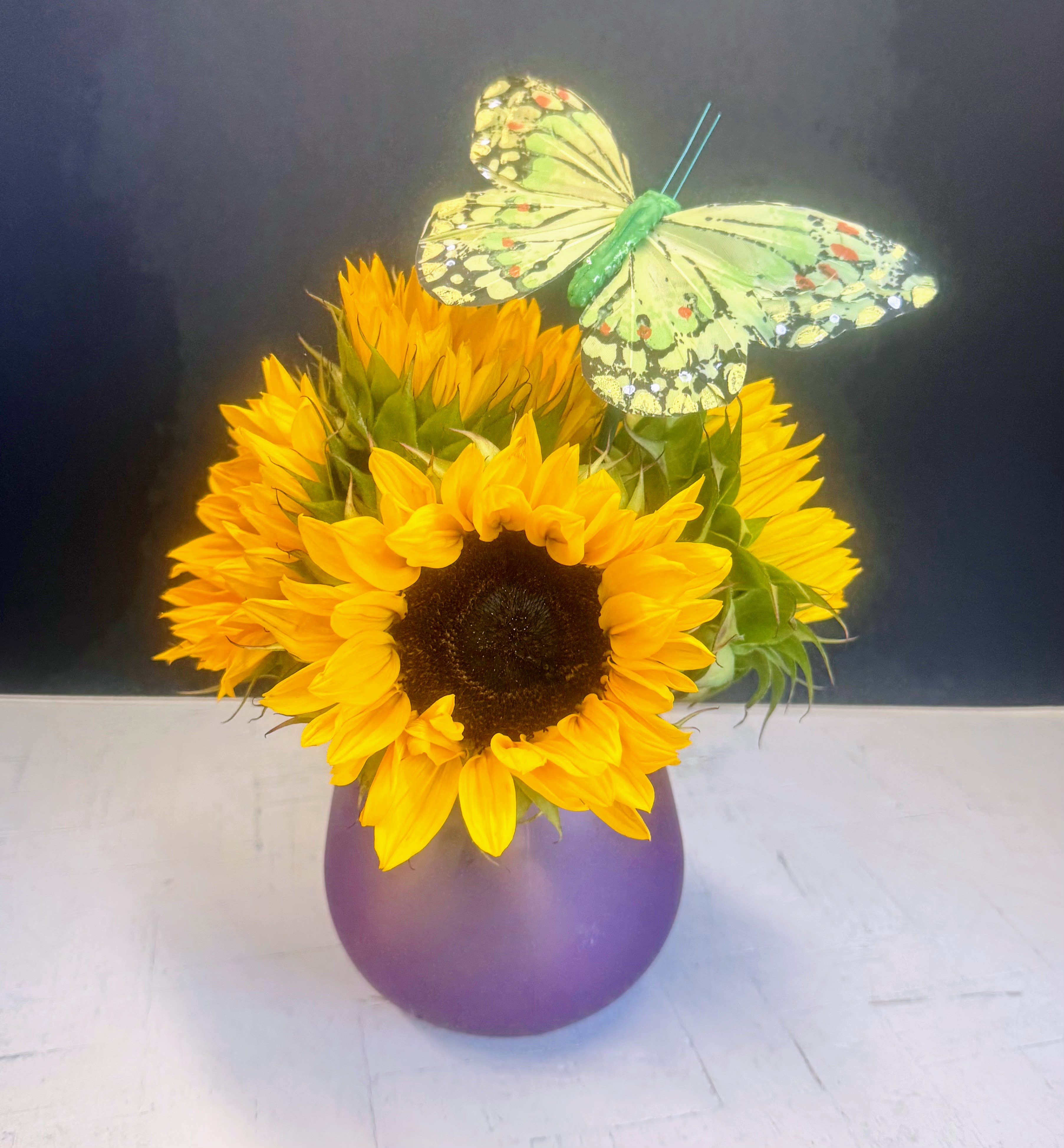 Sunflower Special - 5 stunting sunflowers arranged in a purple bubble vase with a silk butterfly.