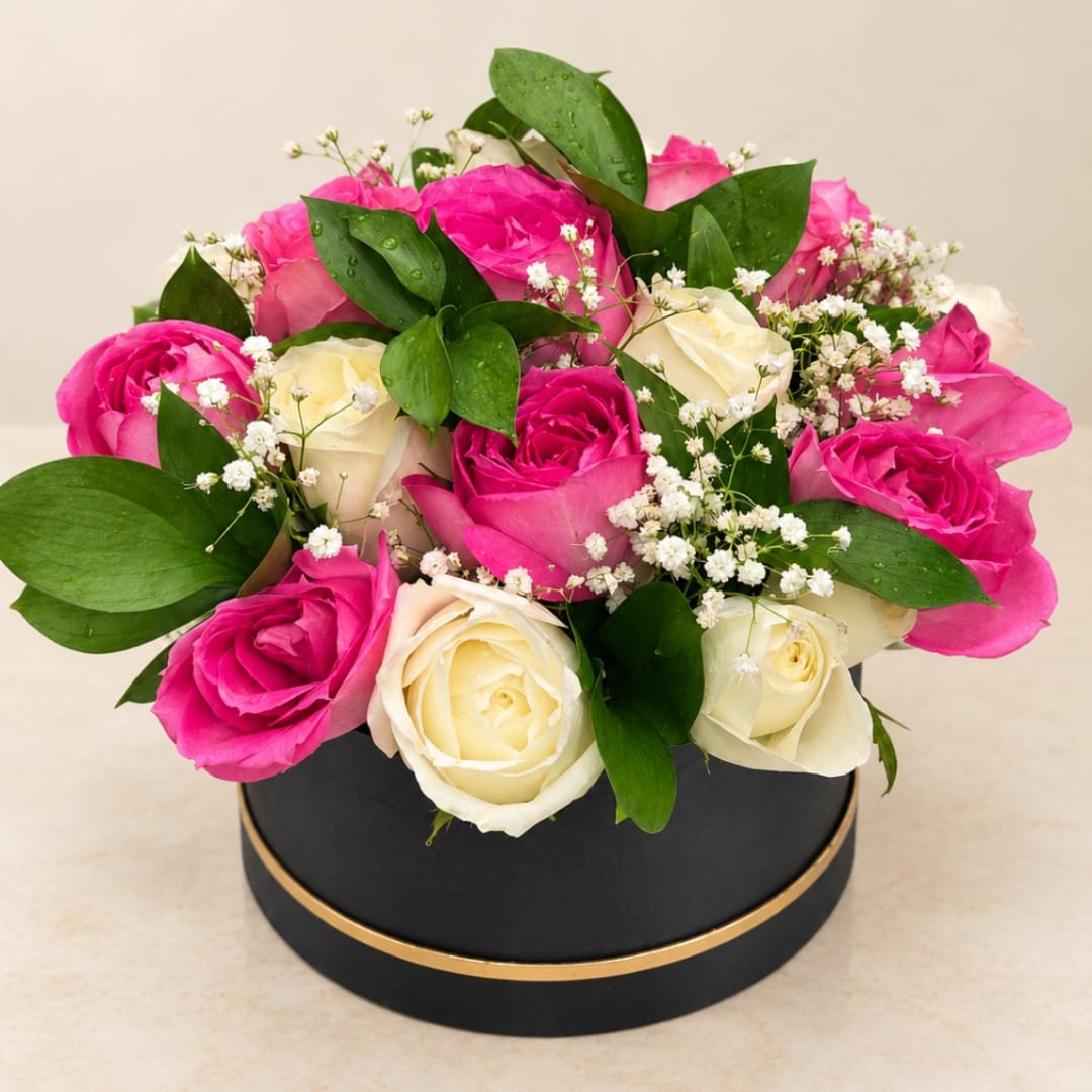 Pink and white roses arranged in a round black box