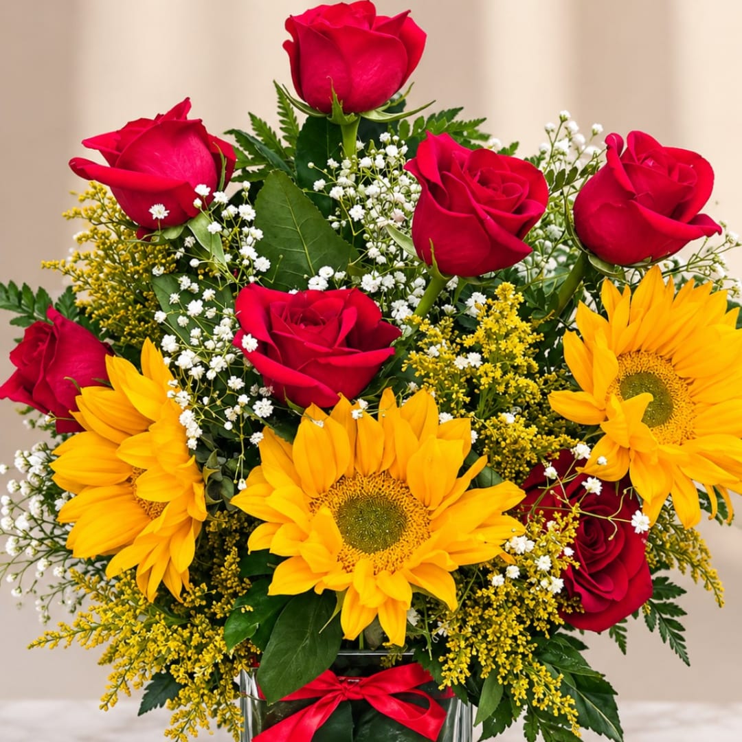 Red roses and yellow sunflowers in a glass vase with baby's breath