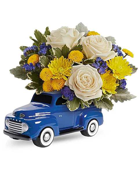 Blue toy truck holding white roses and yellow flowers
