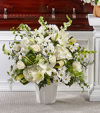 White floral arrangement in a white vase with lilies and daisies
