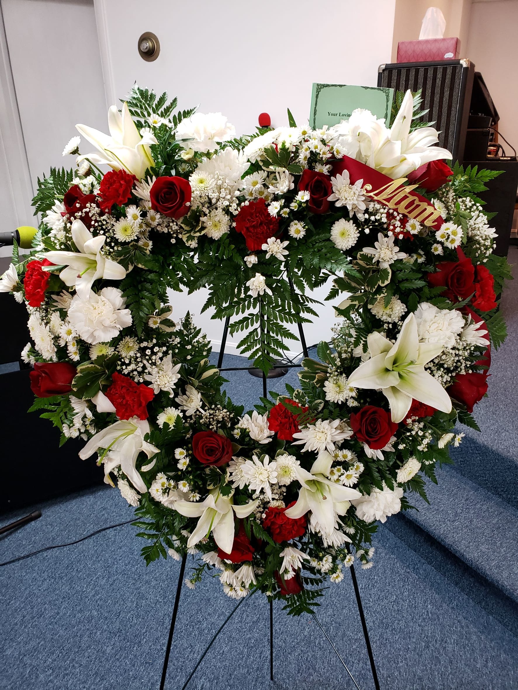 Heart-shaped floral wreath with white lilies, red roses, and white daisies