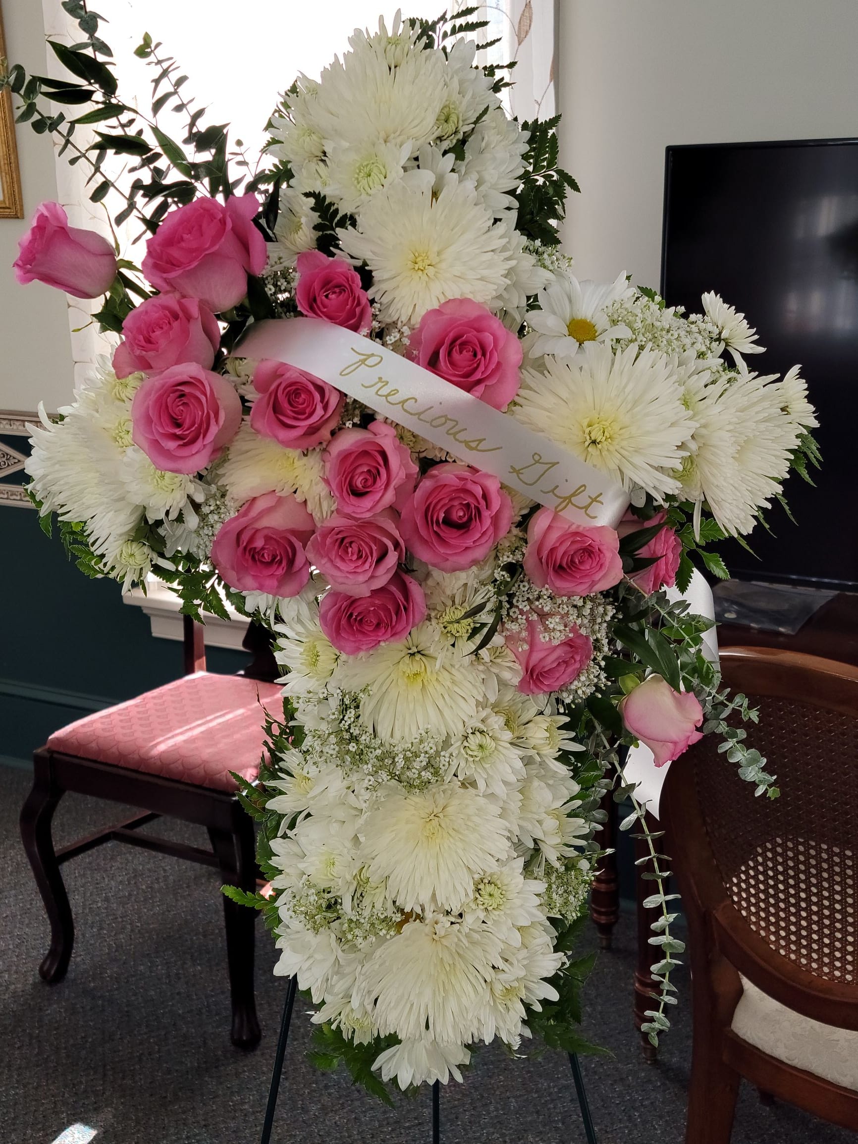 Pink roses and white chrysanthemums in a standing spray with a ribbon