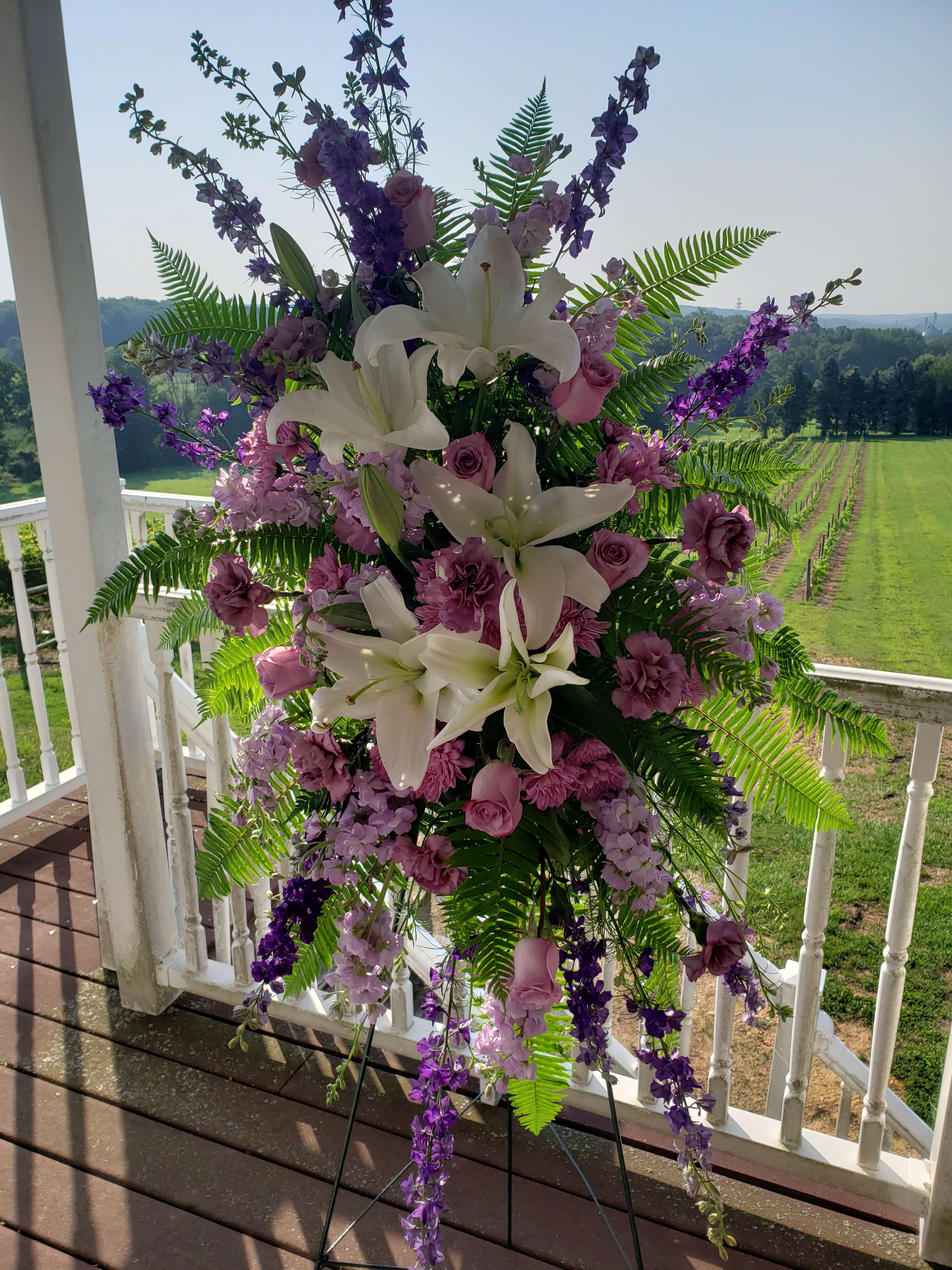 Tall floral standing spray with white lilies and purple blooms