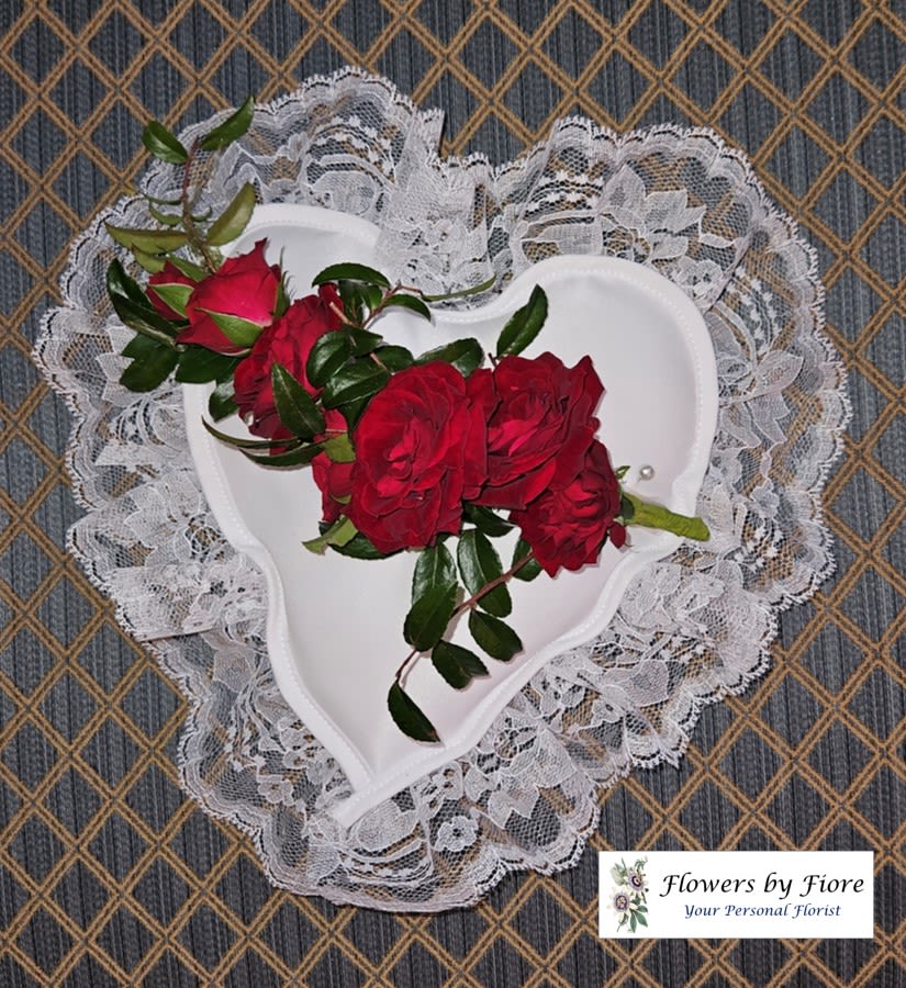 Red roses arranged in a white heart-shaped holder with lace trim