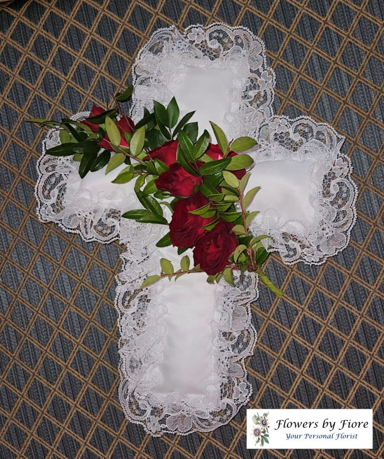 Red roses and greenery arranged on a white lace cross