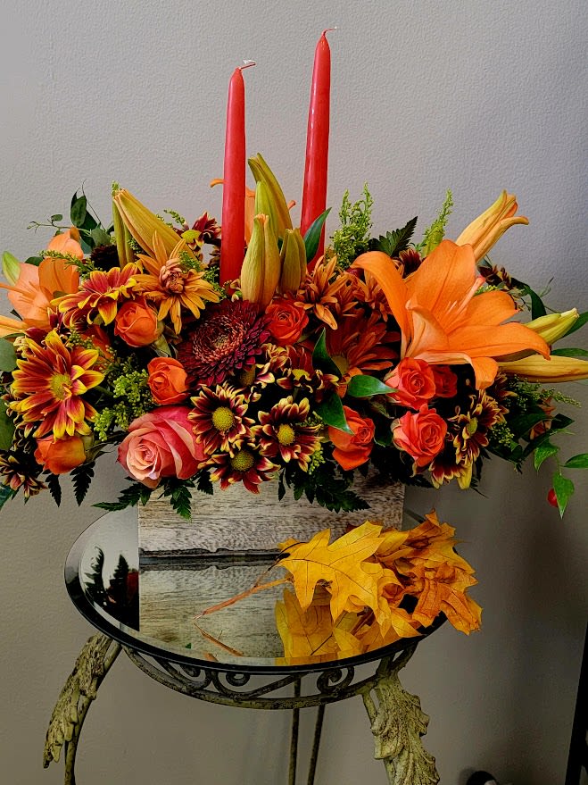 Fiore's Two Candle Autumn Centerpiece - Fresh fall florals arranged in a wooden rectangular box and accented with two bittersweet orange candles and fall foliage and berries.  SPECIAL REQUESTS can be made if ordering by phone or online in the special instruction section of the item. Candle color and flowers can be customized.  Standard, 12x6x5 Deluxe (most popular), 14x7x6 Premium, 16x8x7 