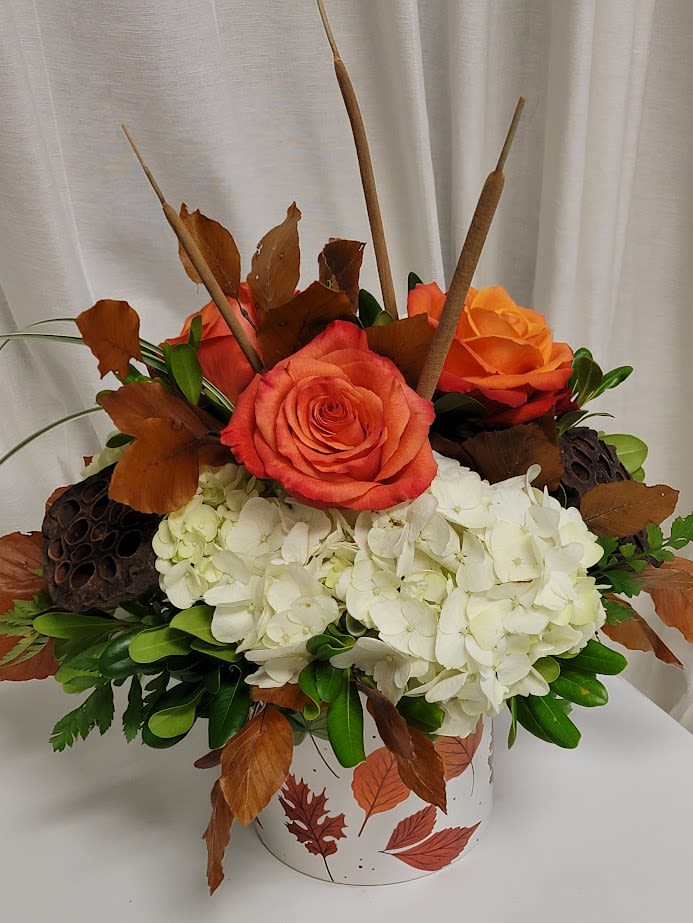 Orange roses and white hydrangeas in a leaf-patterned container