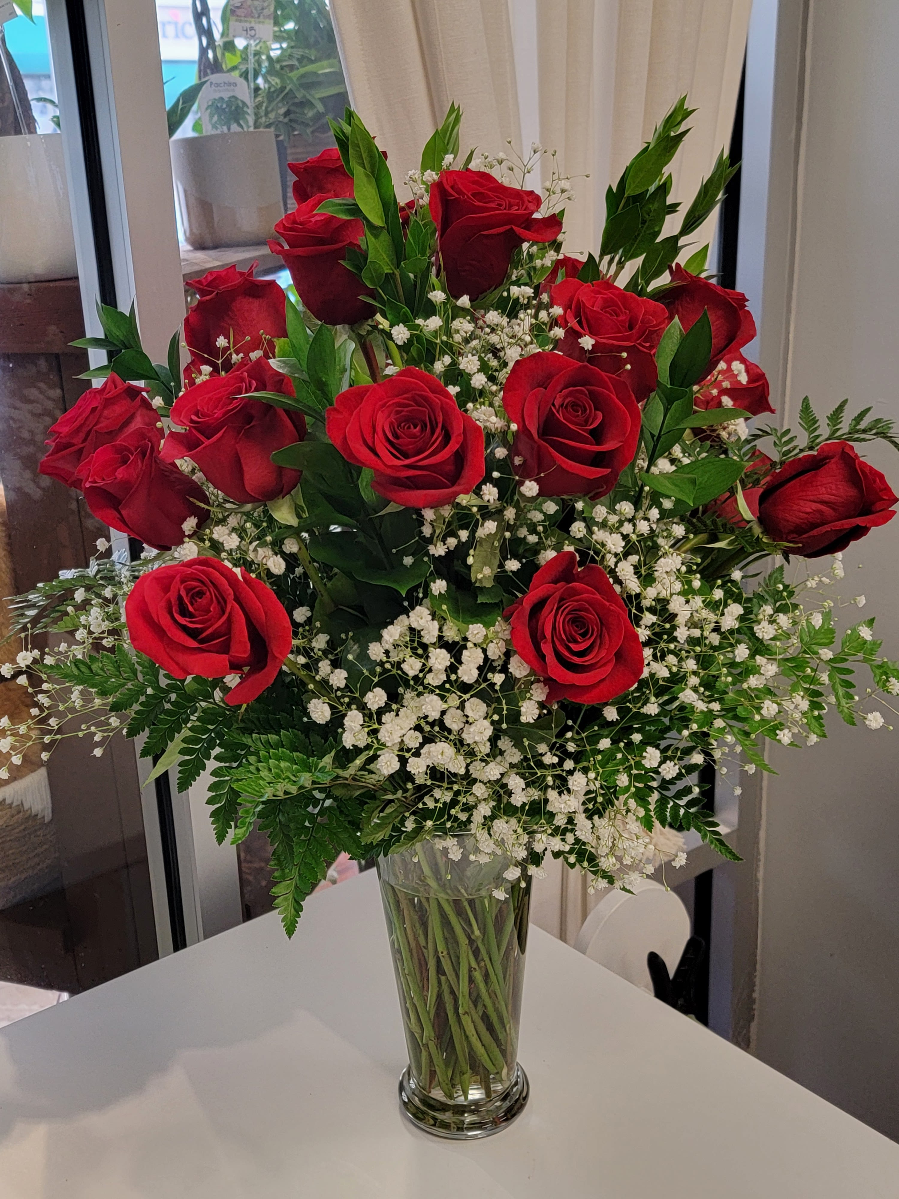 Red roses arranged in a clear glass vase with white baby's breath