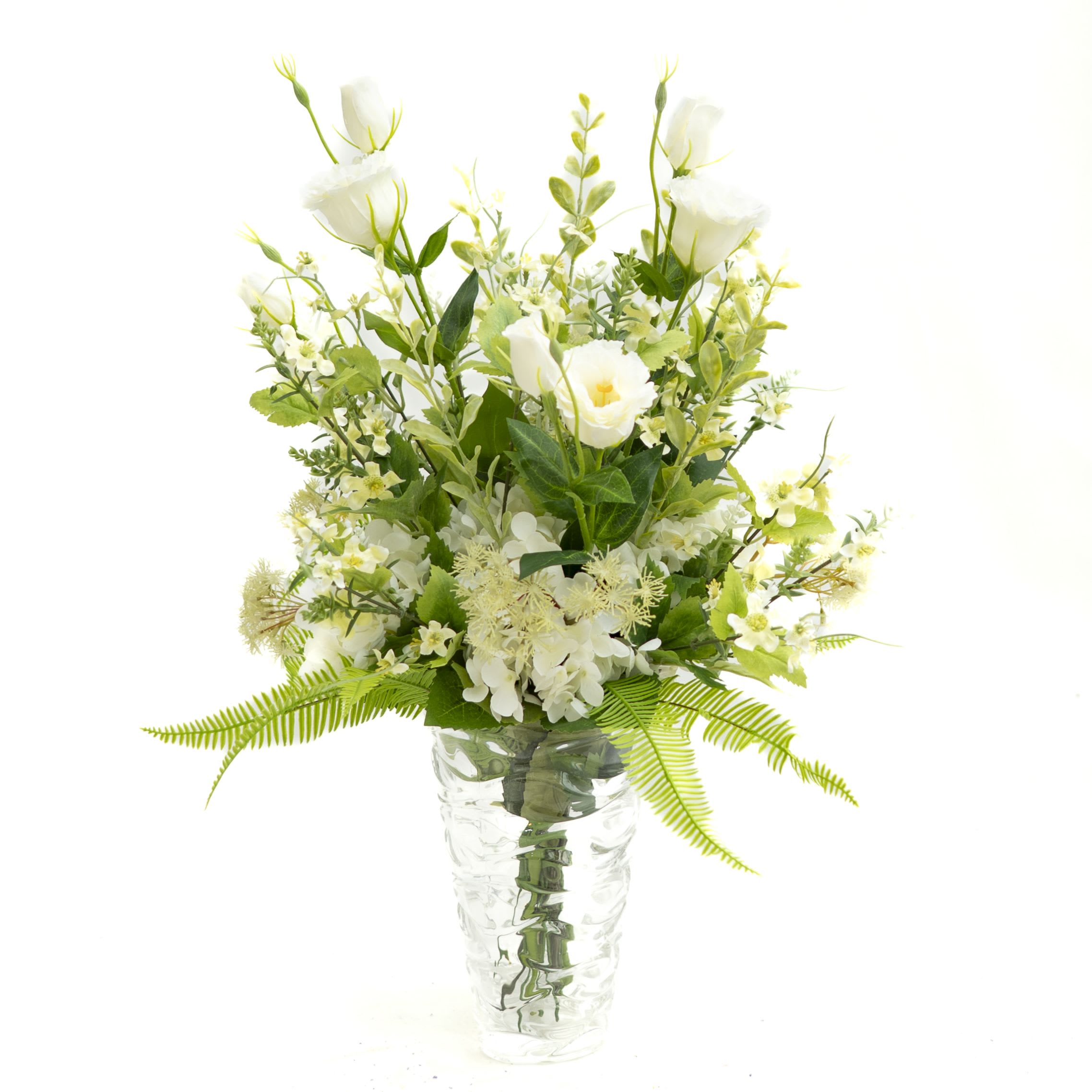 White floral arrangement in a clear glass vase with fern accents