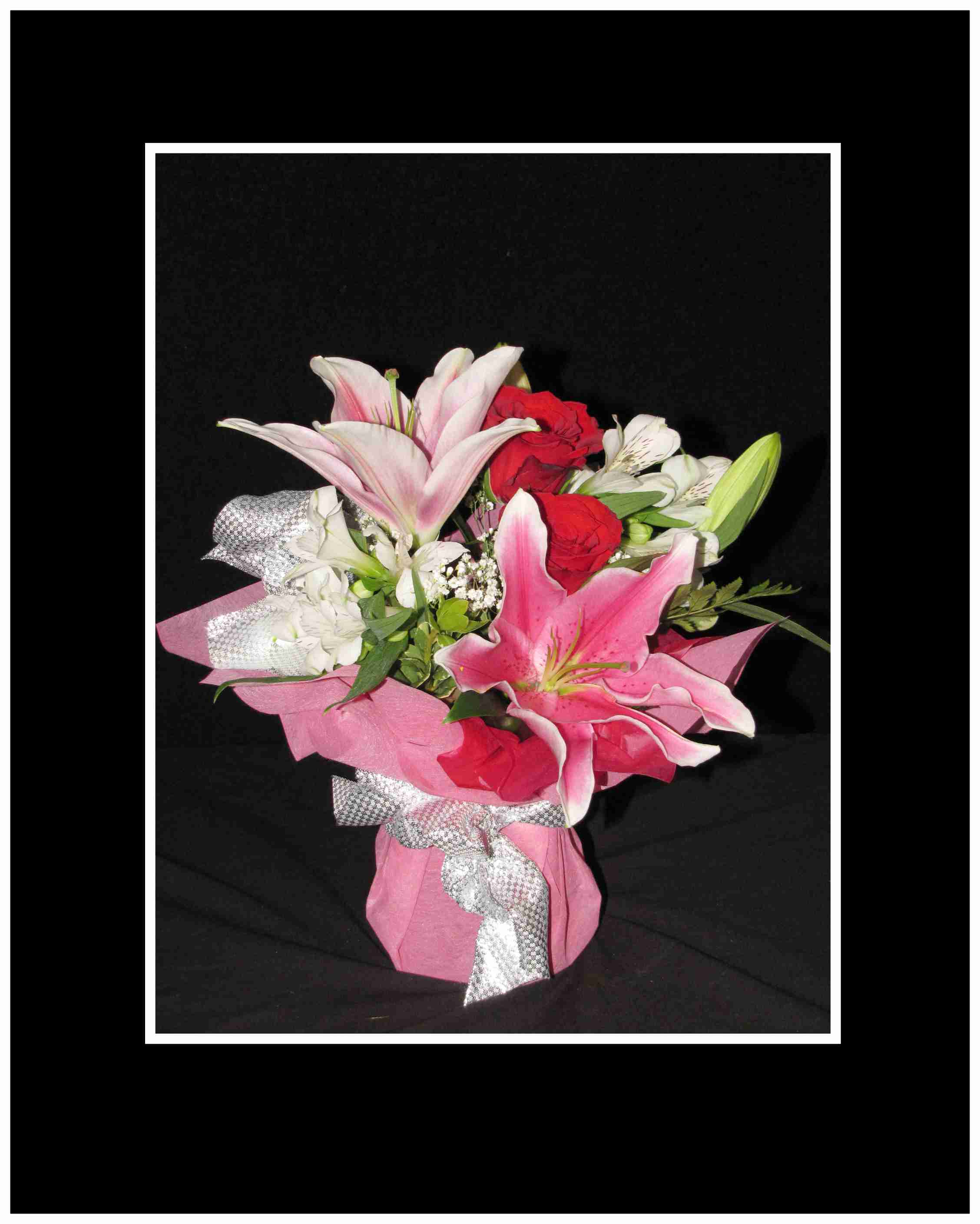 Bouquet of pink lilies and red roses wrapped in pink paper