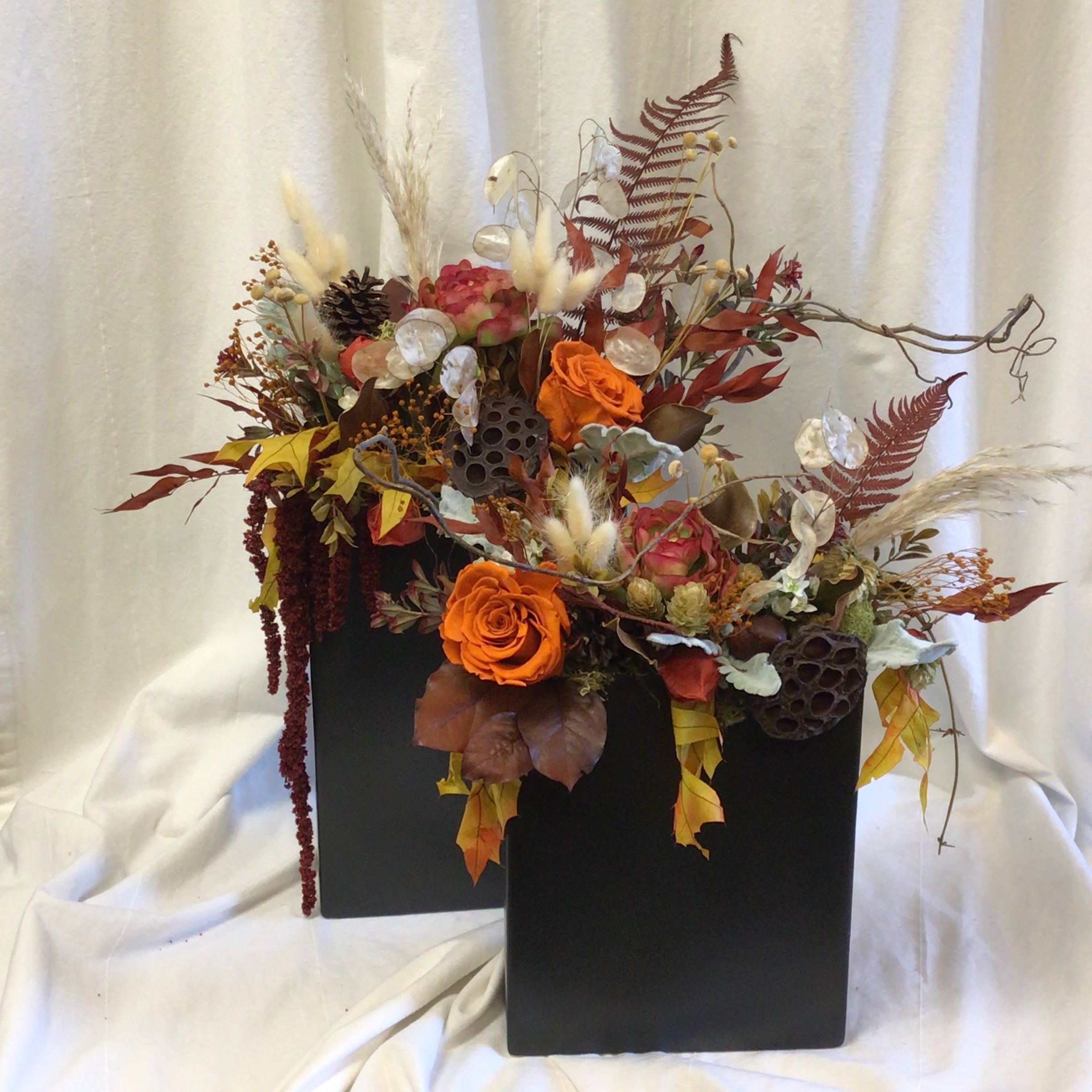 Autumn floral arrangement with orange roses in a black vase