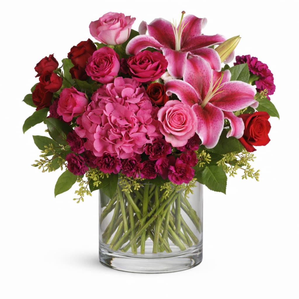 Pink lilies and roses arranged in a clear glass vase