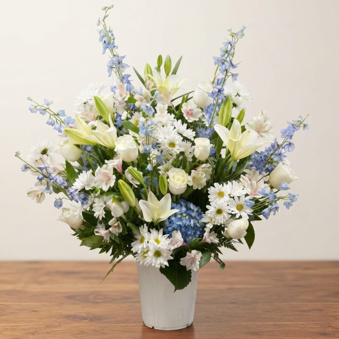 White and blue mixed flower arrangement in a white vase