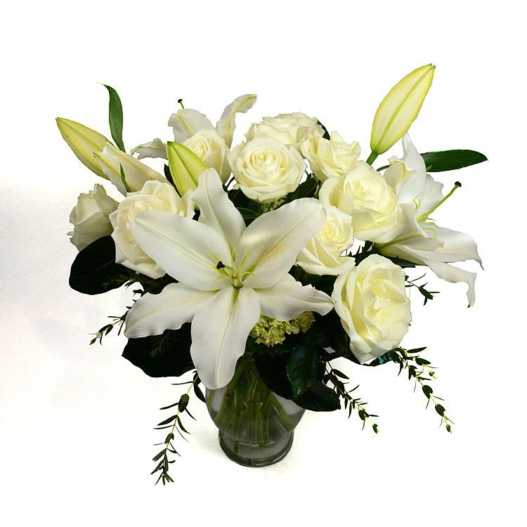 White lilies and roses arranged in a glass vase