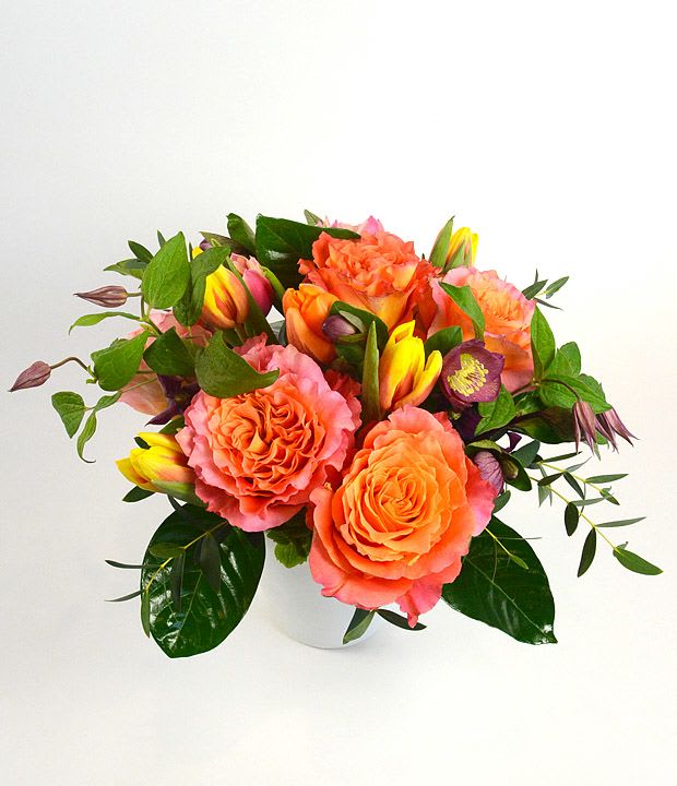 Orange and pink rose bouquet in a white vase