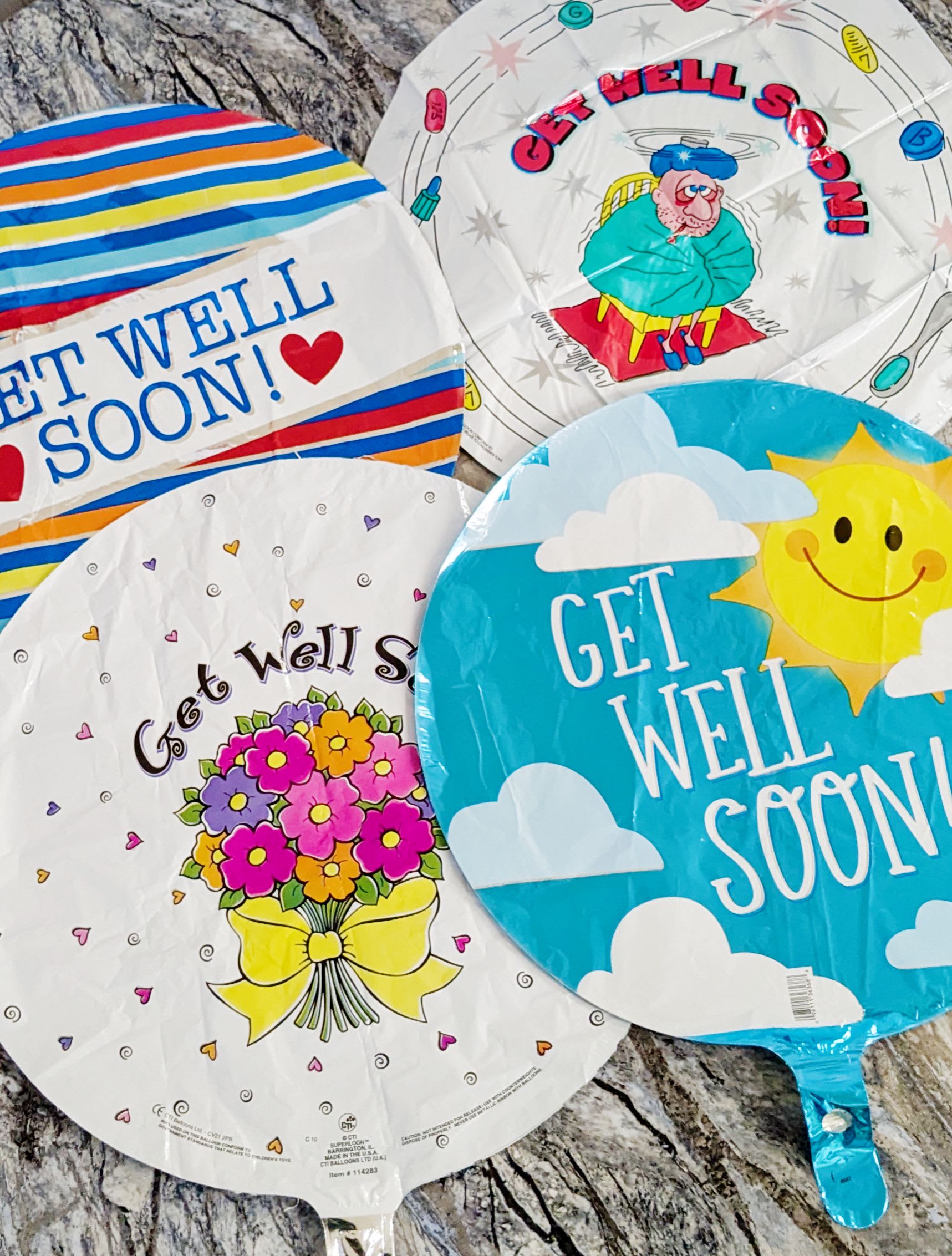 Four round get-well balloons with colorful printed designs