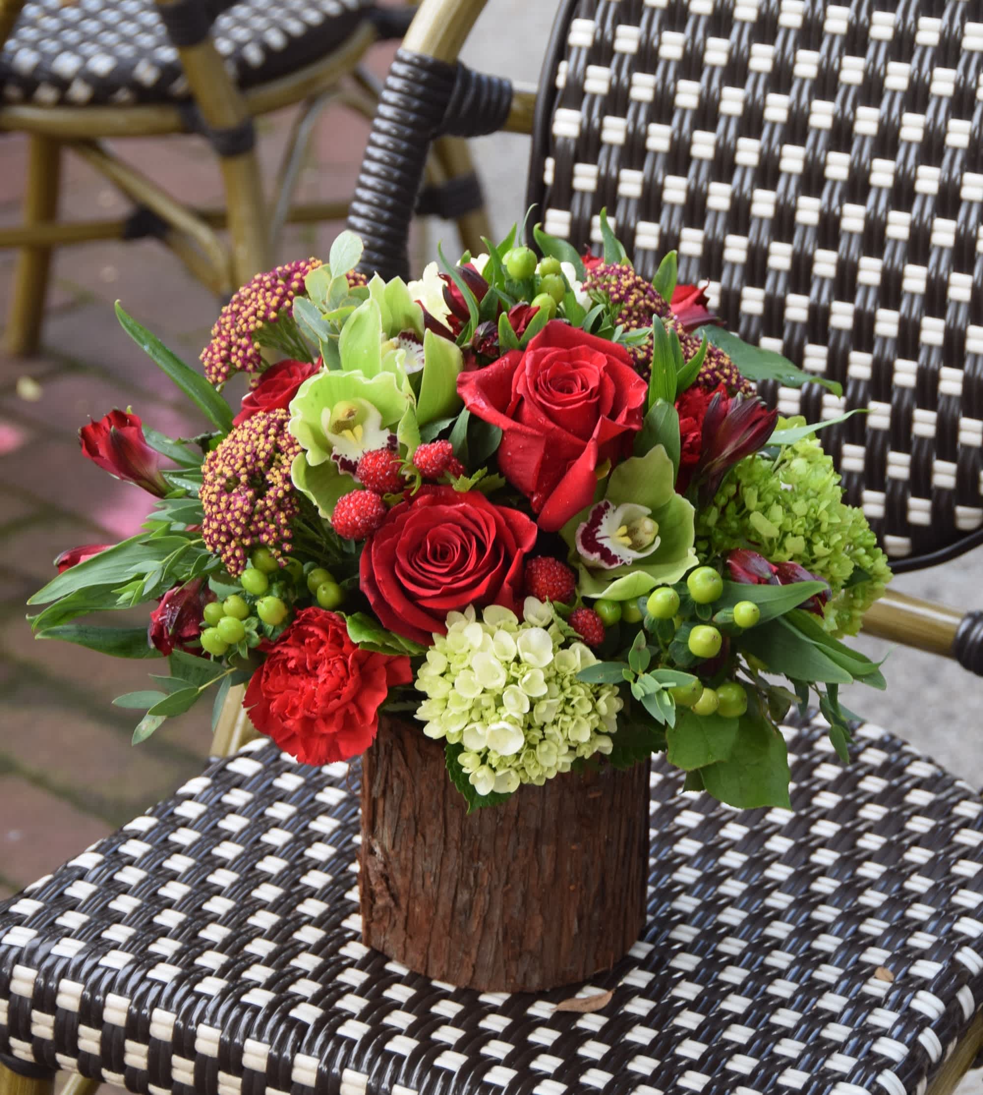 Rustic low arrangement of red roses and green blooms in a wood-look vase