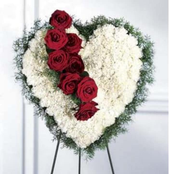 Heart-shaped floral spray with red roses and white flowers on an easel