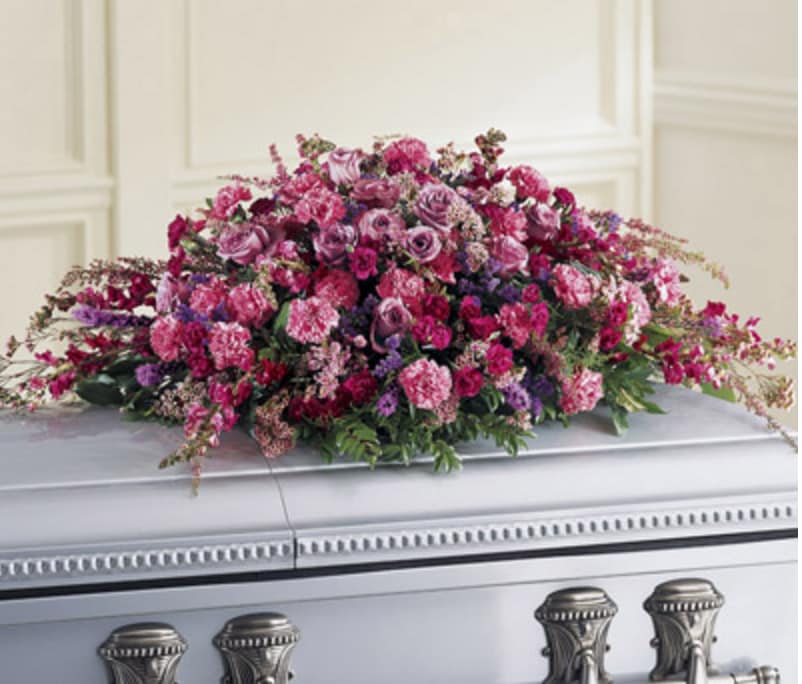 Large pink and purple floral spray on a casket