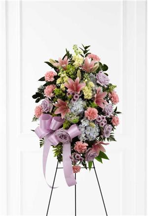 Standing floral spray with pink and lavender blooms on a black easel