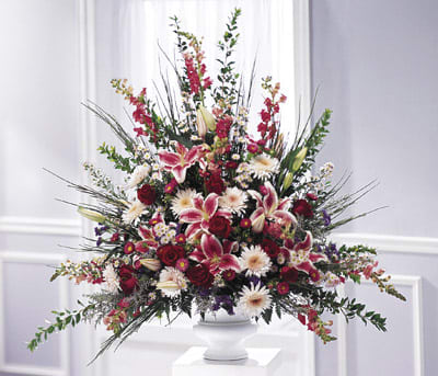 Large mixed floral arrangement in a white pedestal vase