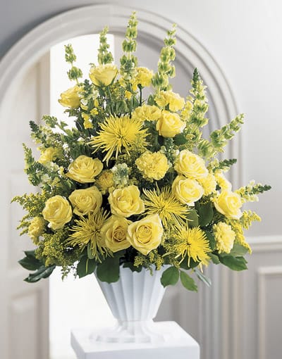 Yellow roses and spider mums arranged in a white vase