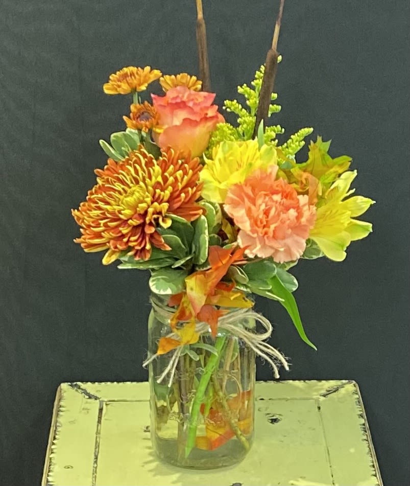 Bright mixed bouquet in a glass jar vase with orange, pink, and yellow blooms