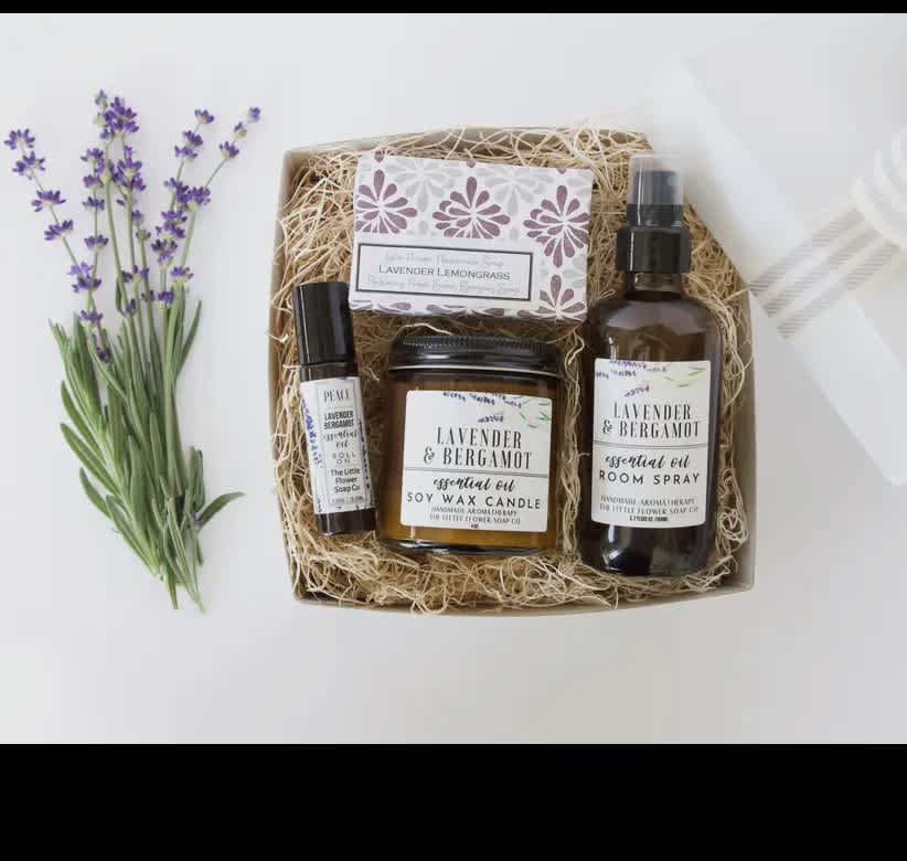 Lavender sprigs beside a gift box with soap, candle, and room spray