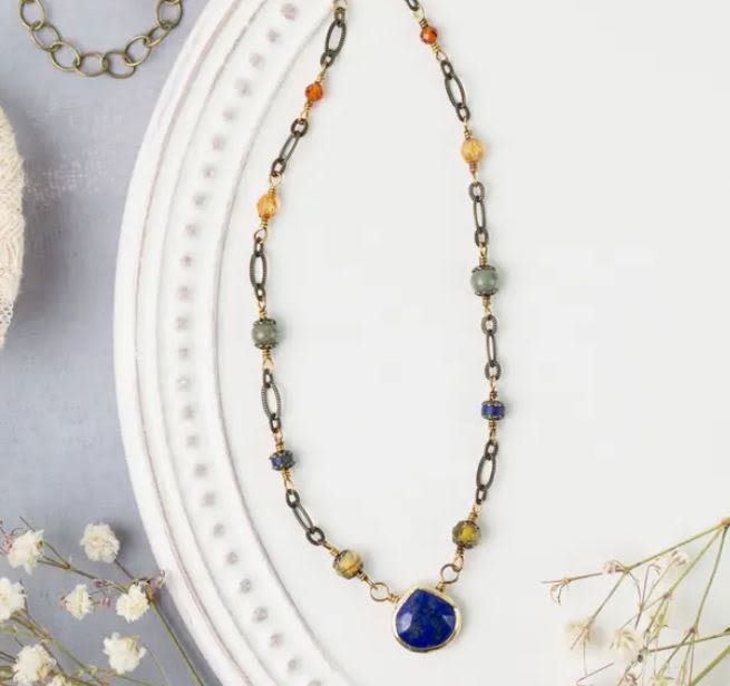 Beaded necklace with a blue pendant on a white display bust
