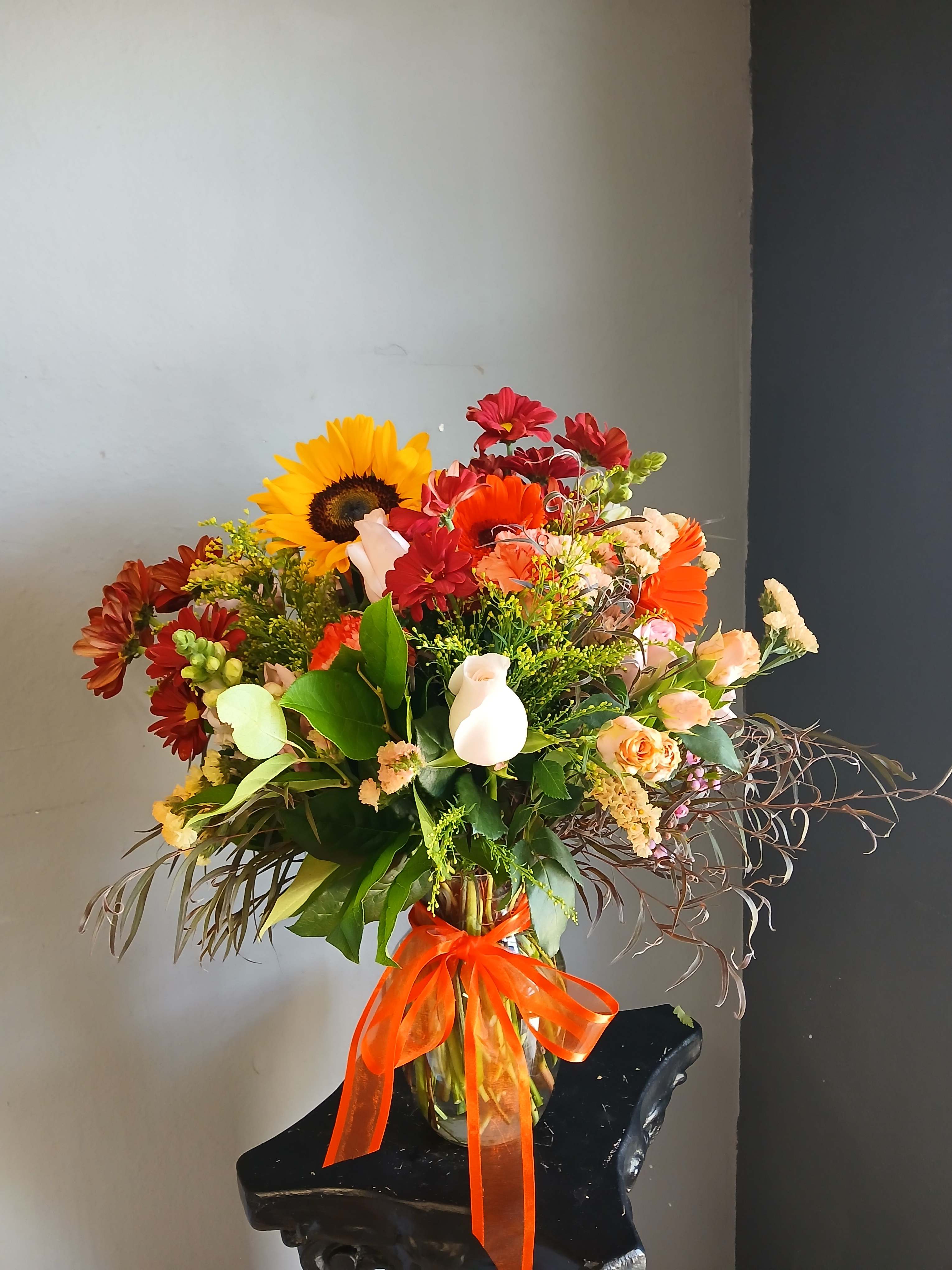 Mixed bouquet in a glass vase with a bright orange ribbon