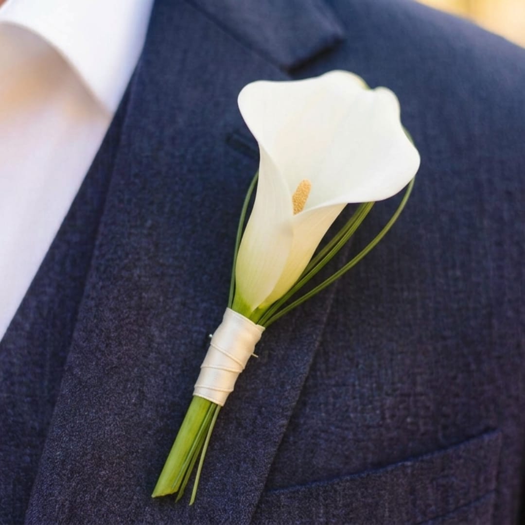 White calla lily boutonniere pinned to a dark suit jacket