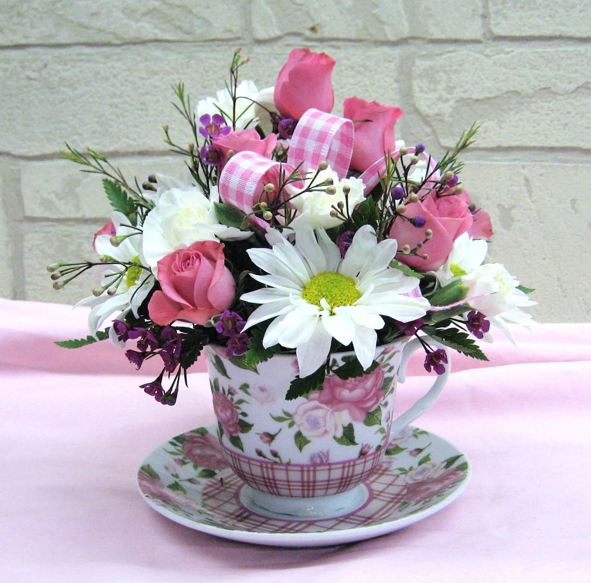 Pink and white flower arrangement in a floral teacup and saucer