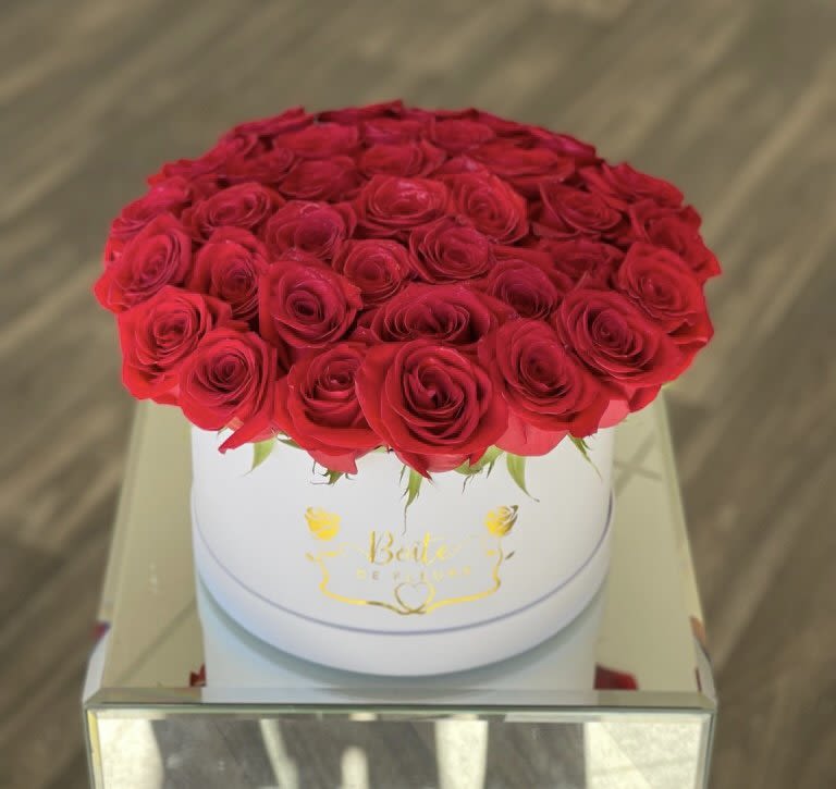 Round box of red roses on a mirrored table