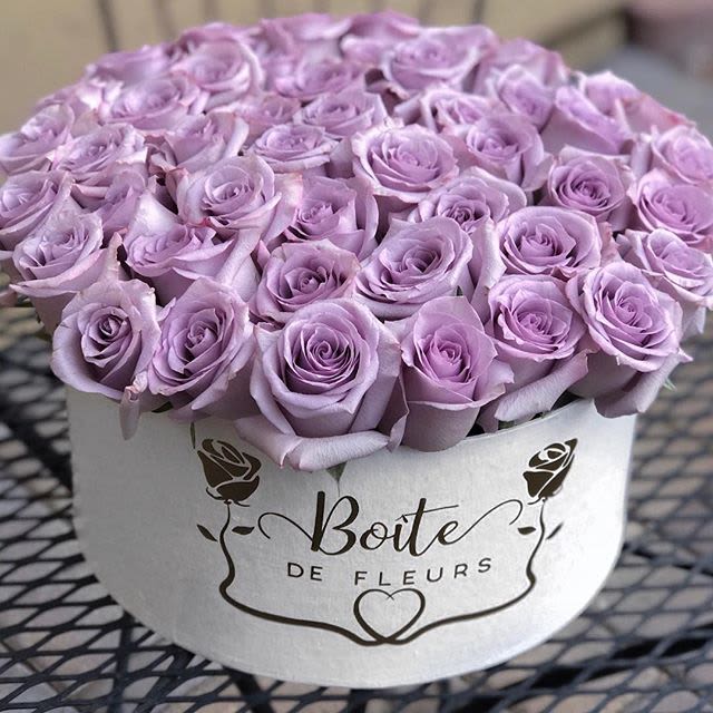 Lavender roses arranged in a round white hat box