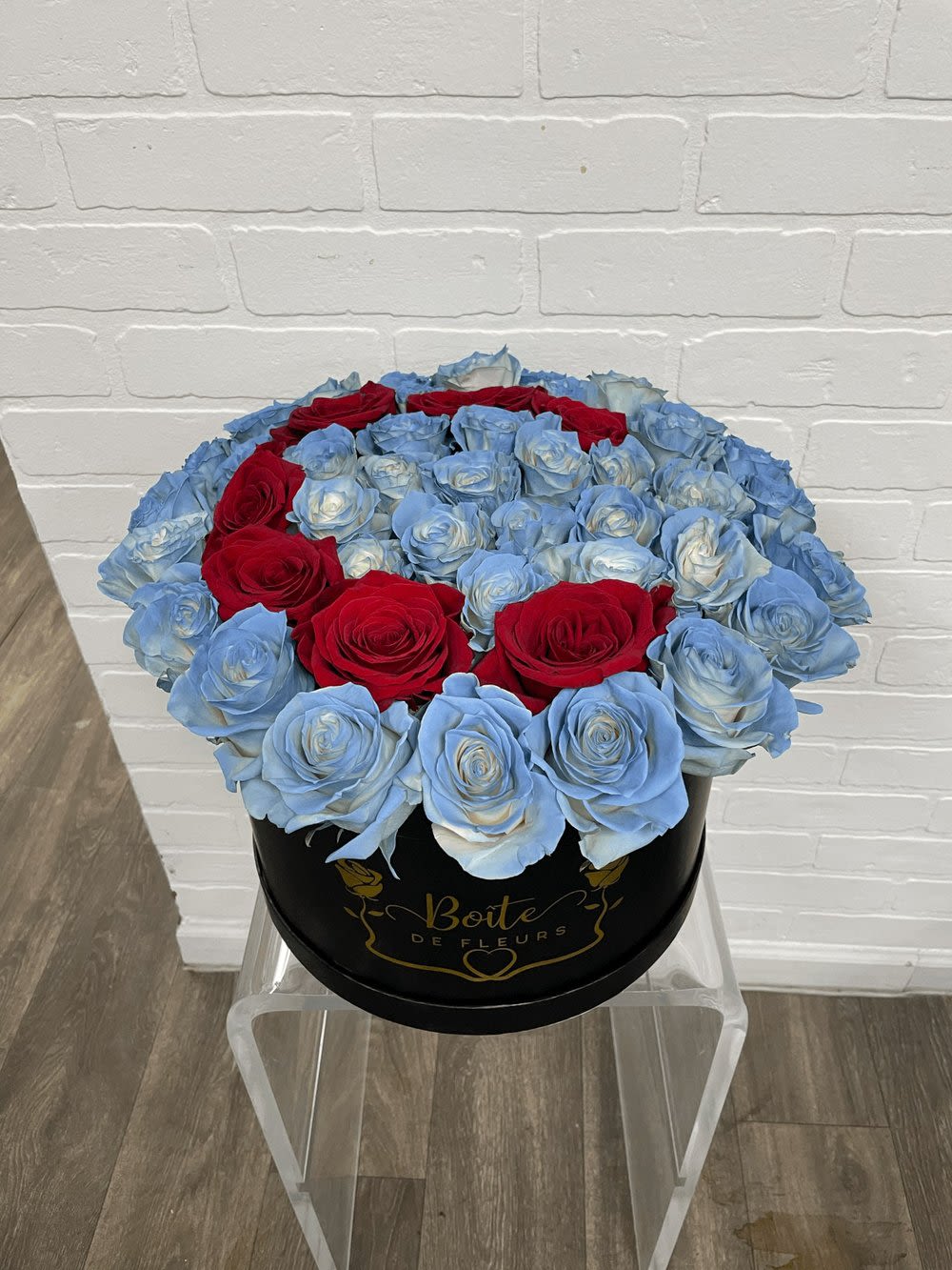 Round box of blue and red roses on a clear stand