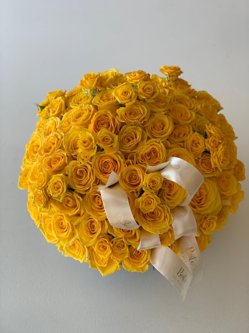 Large round bouquet of yellow roses with white ribbon